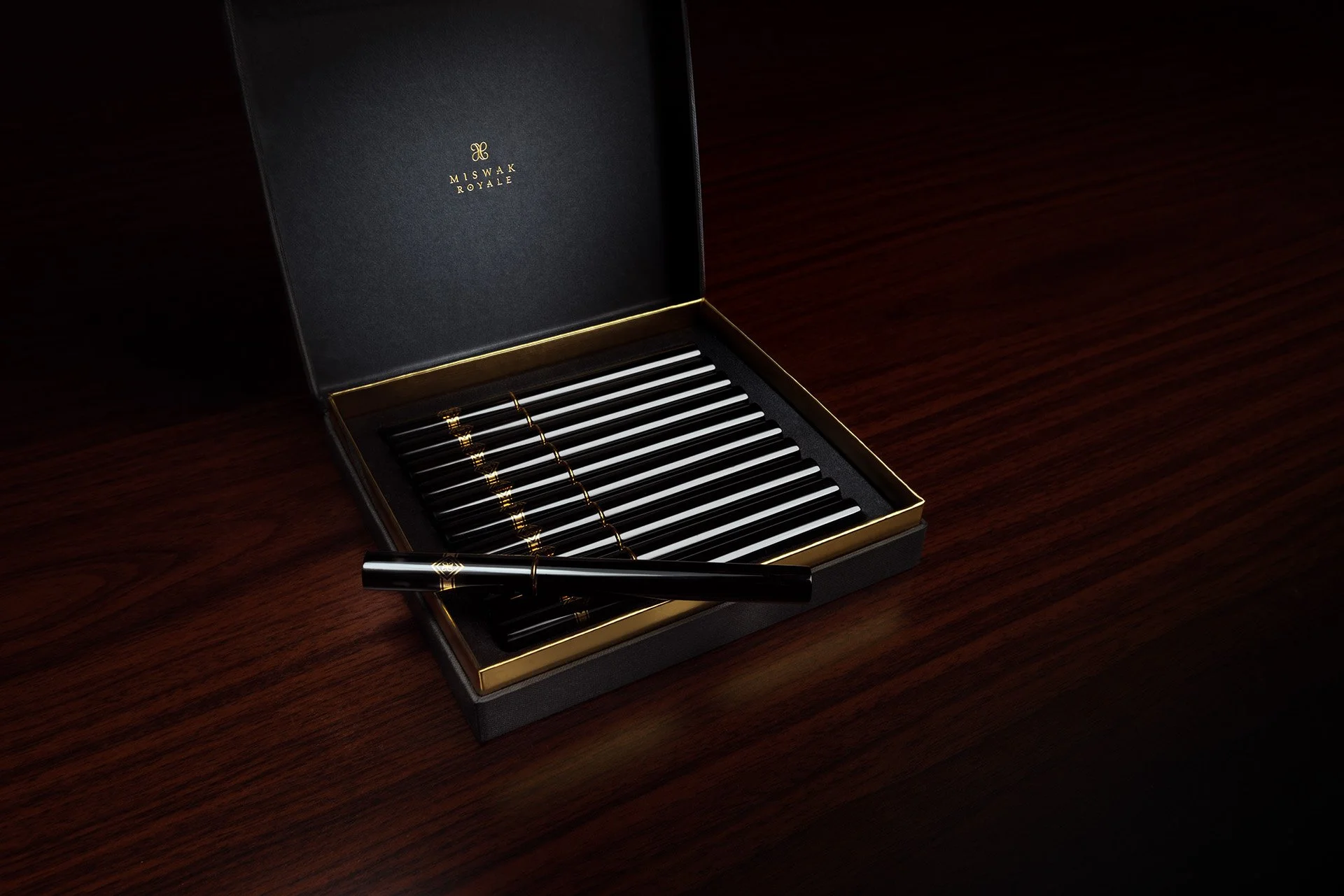 Commercial product shoot of open multi pack Miswak Royale luxury gift box displaying individual black cases on mahogany background by Hammad Iqbal