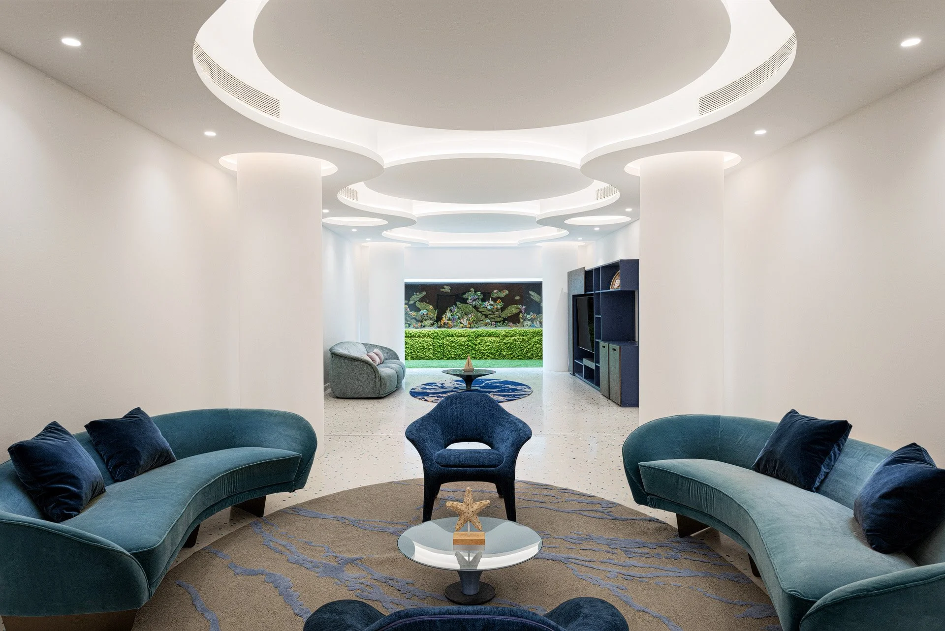 Curved blue seating in a circular formal lounge with layered recessed cove ceiling lighting in a Qatar beach house by Hammad Iqbal