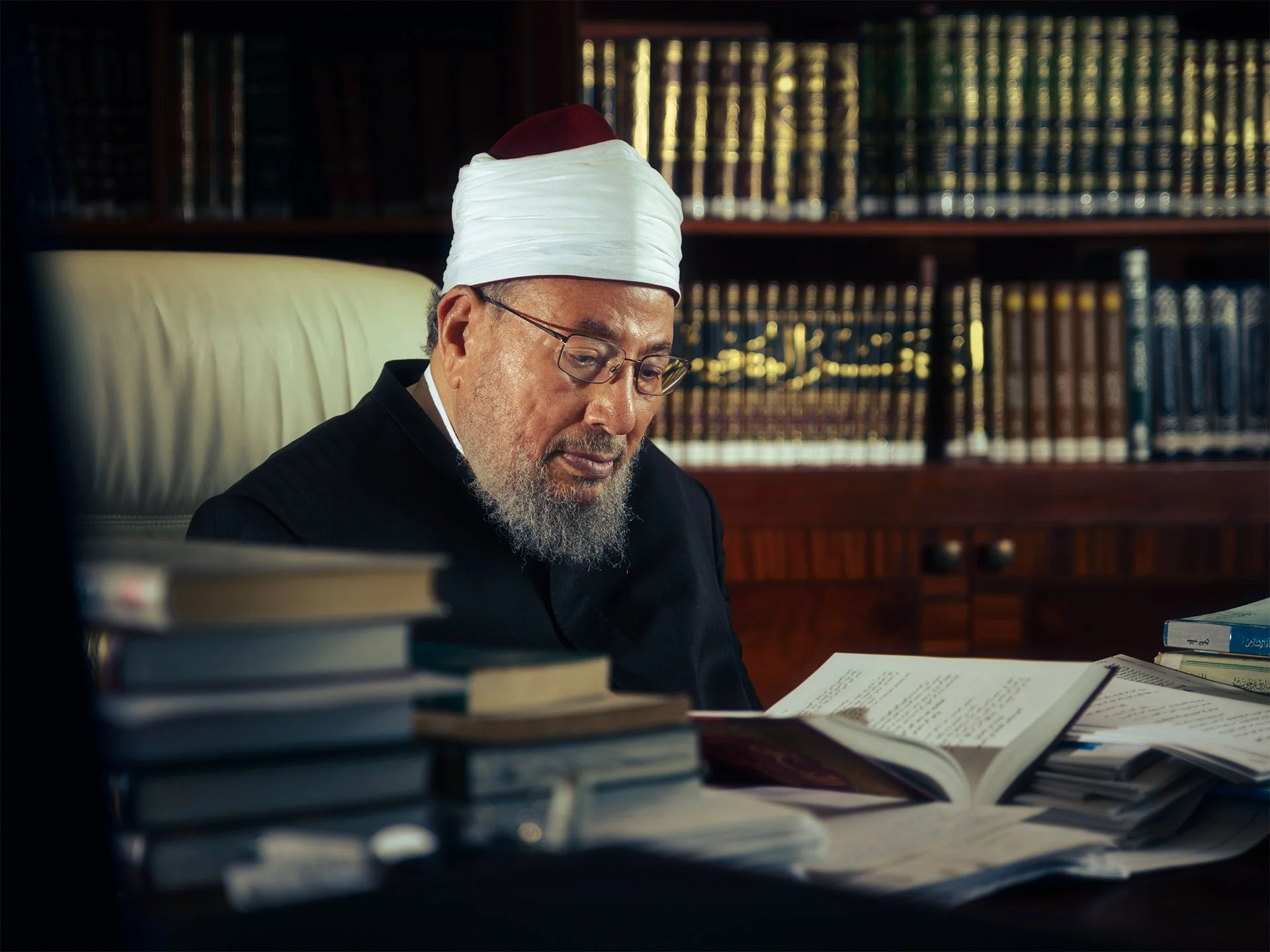 Close up environmental shot of Sheikh Yusuf Al-Qaradawi reading intently with soft octabox studio lighting by Hammad Iqbal