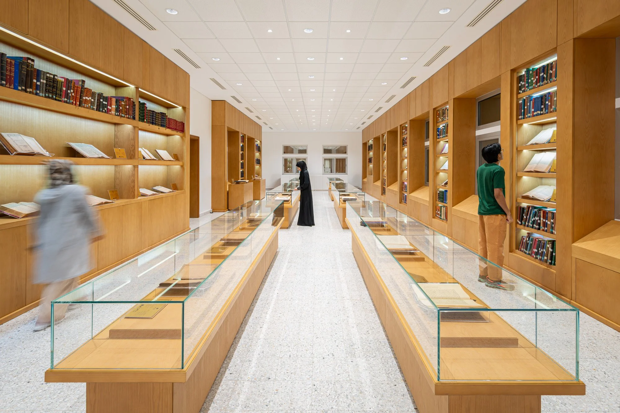 Illuminated oak shelving and glass display cases inside the Hall of Rare and Heritage Books at Dar Al Kutub library shot by architectural photographer Hammad Iqbal