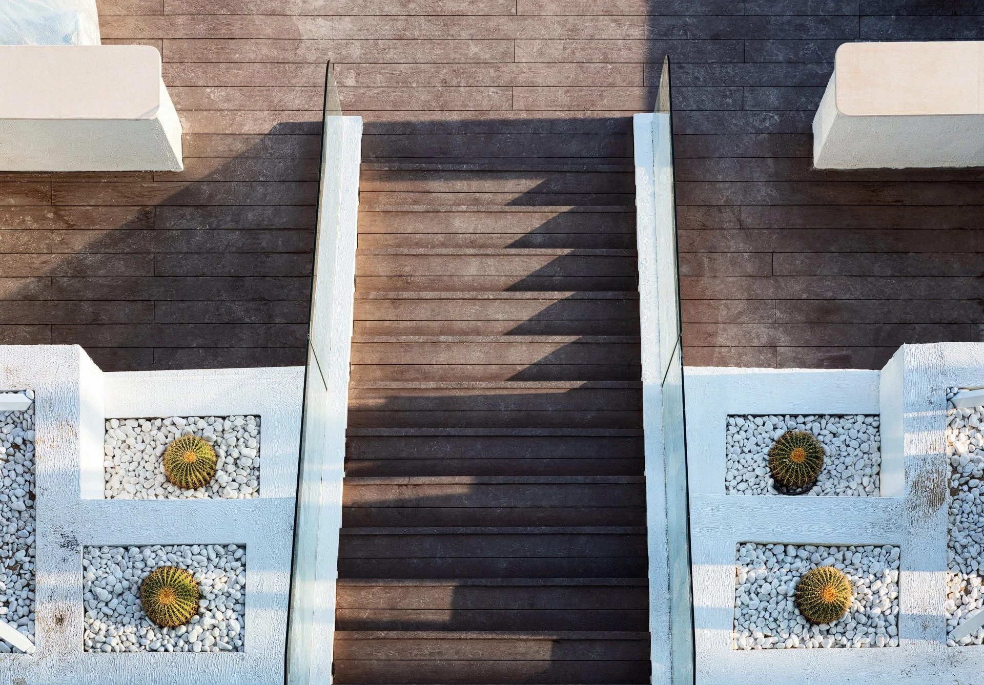Direct overhead top-down photo of a rich timber staircase with glass railings and marble borders photographed by Hammad Iqbal