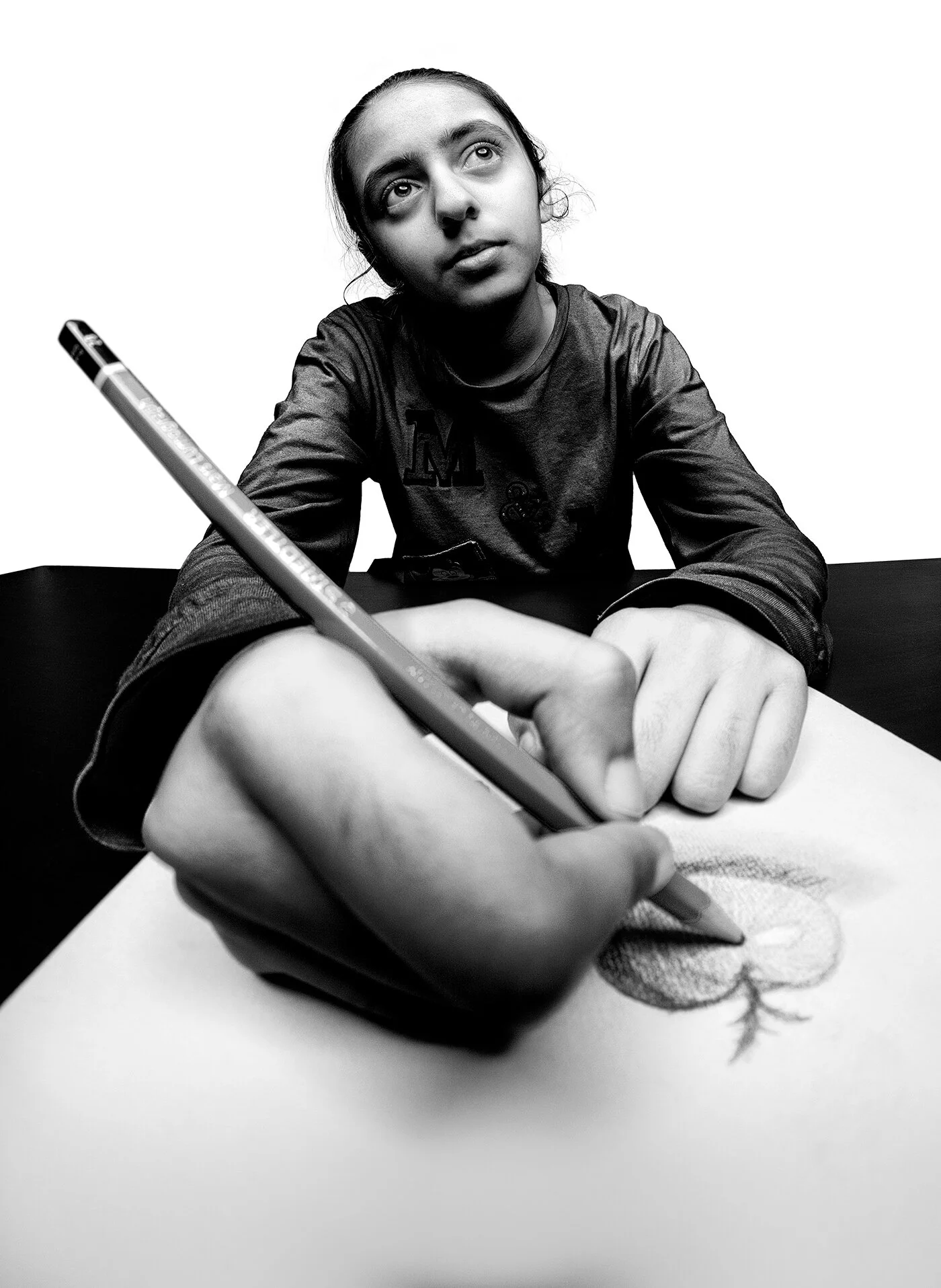 Forced perspective black and white photo of girl holding large pencil drawing an apple by Hammad Iqbal