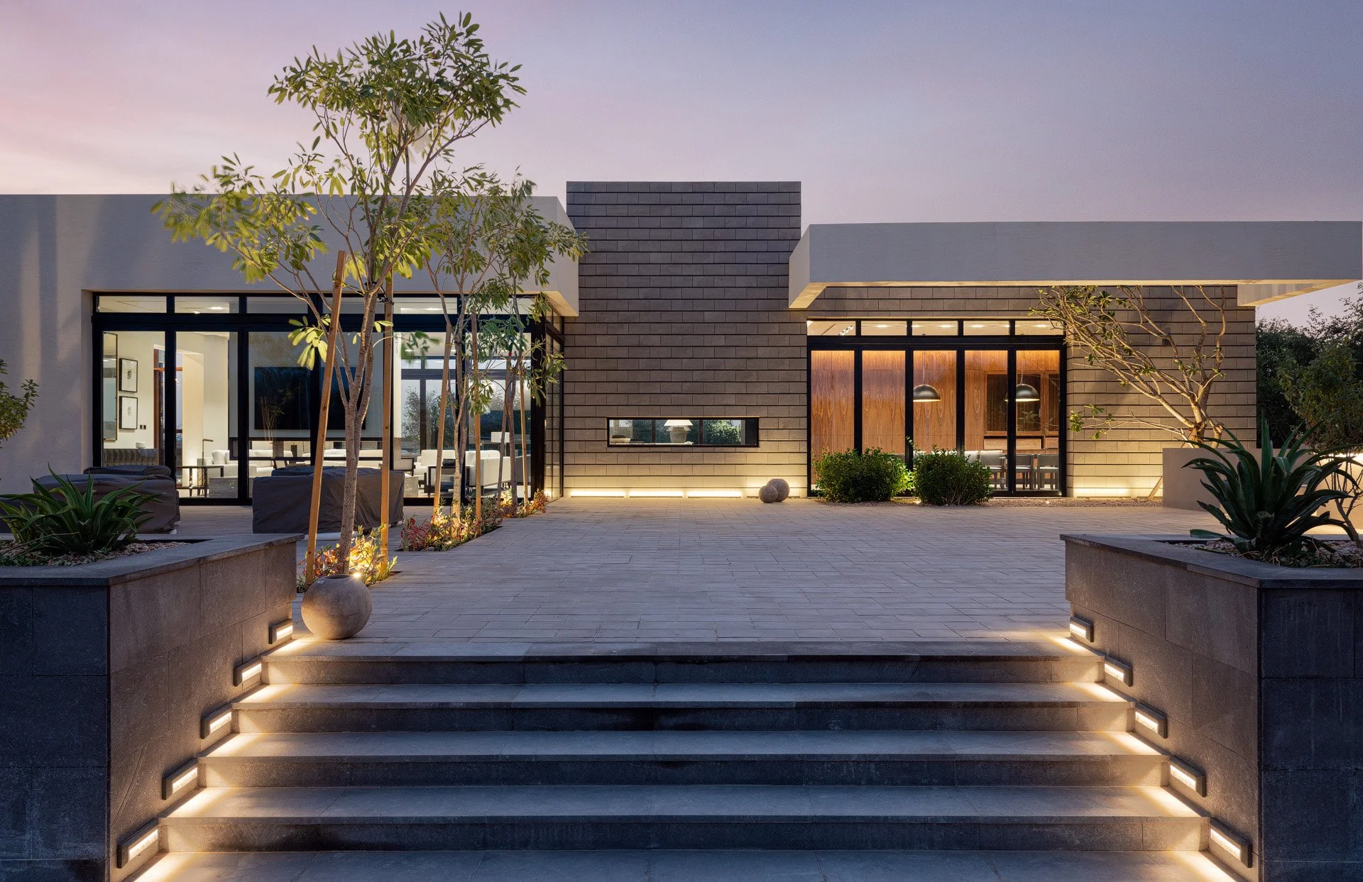 Illuminated outdoor plaza and terraced stone steps of a modern luxury estate pavilion in Qatar photographed by Hammad Iqbal