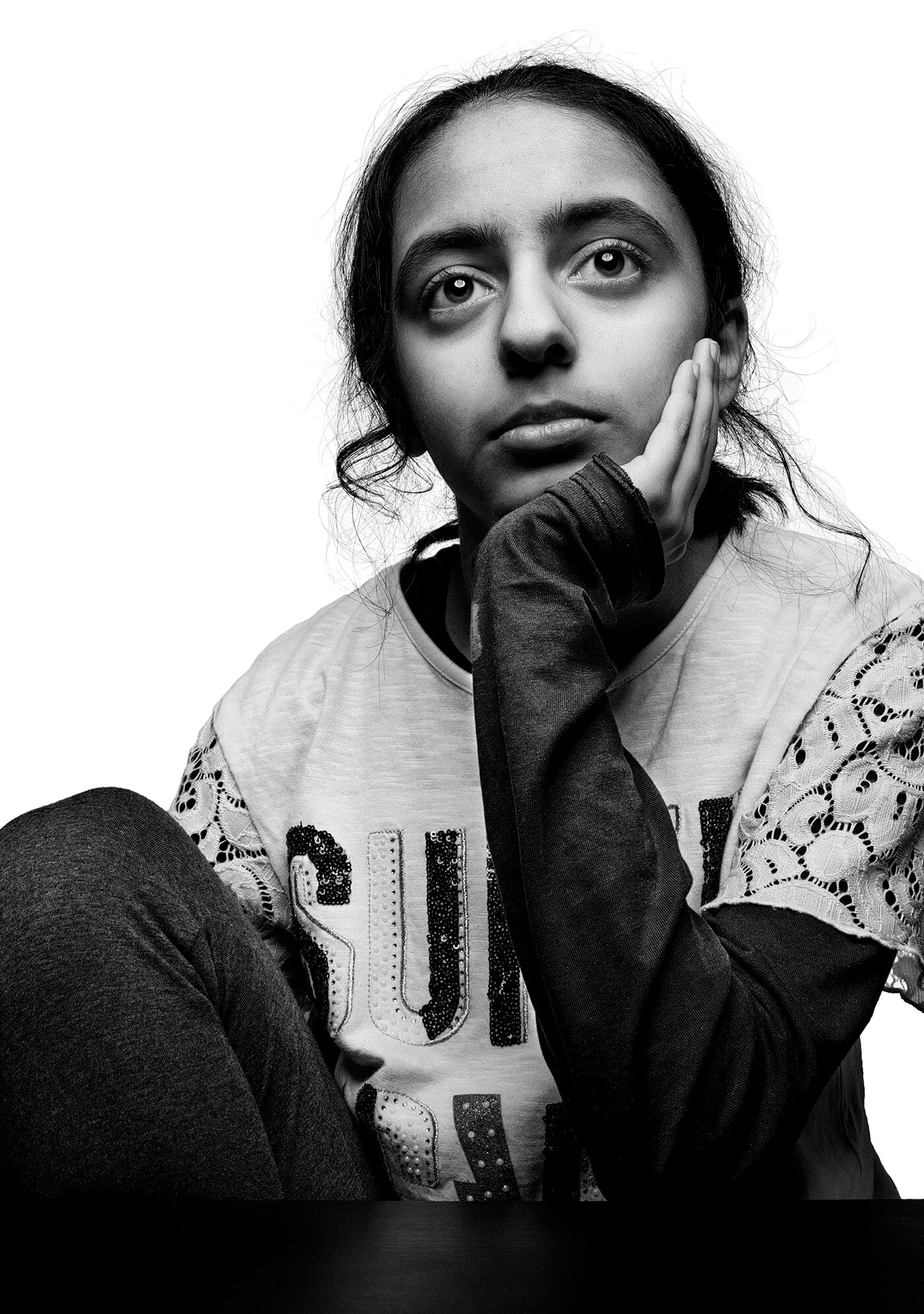 Monochrome portrait of young girl leaning on hand in isolation study by Hammad Iqbal