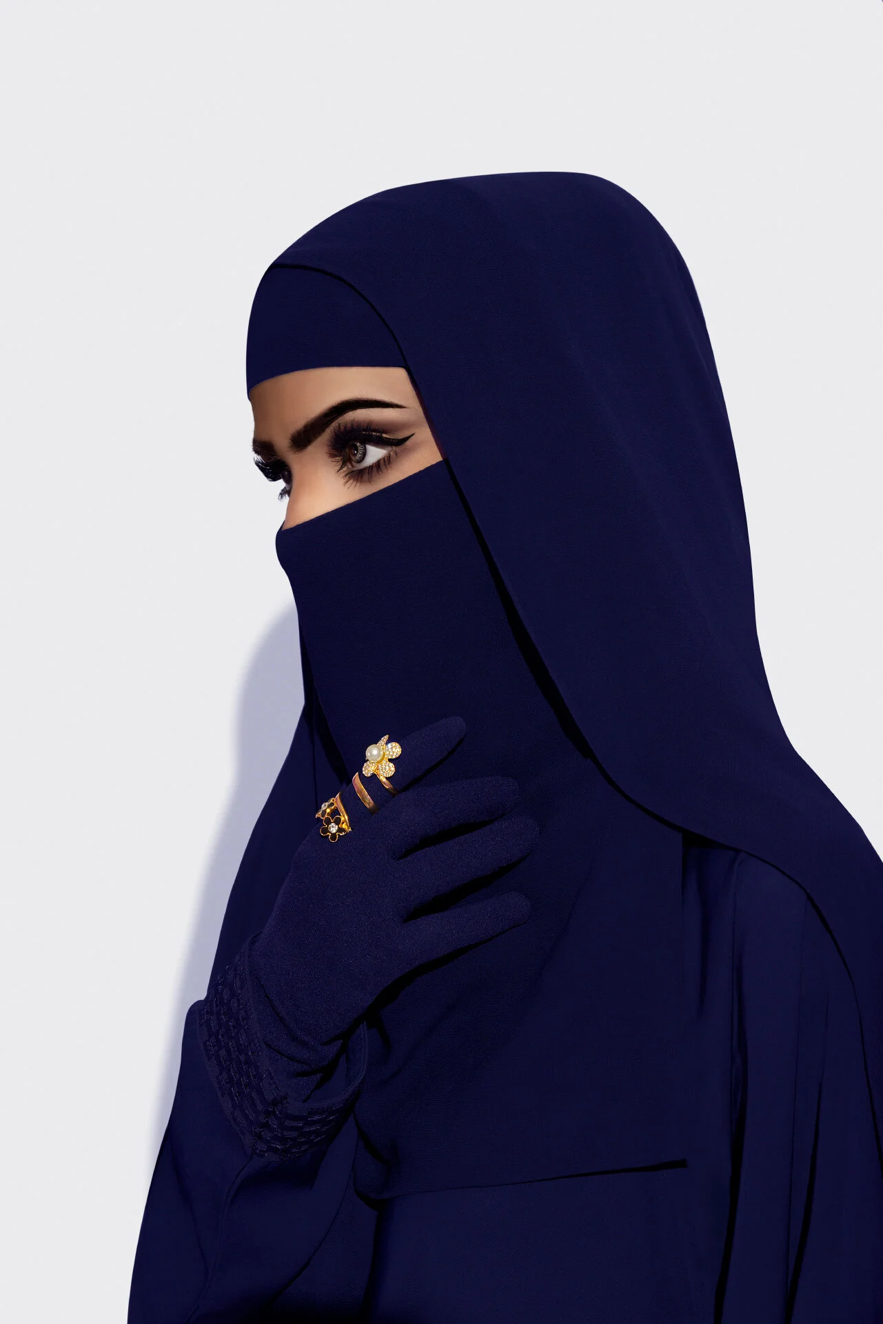 Close up editorial portrait of a woman in dark navy niqab displaying gold ring jewelry by Hammad Iqbal