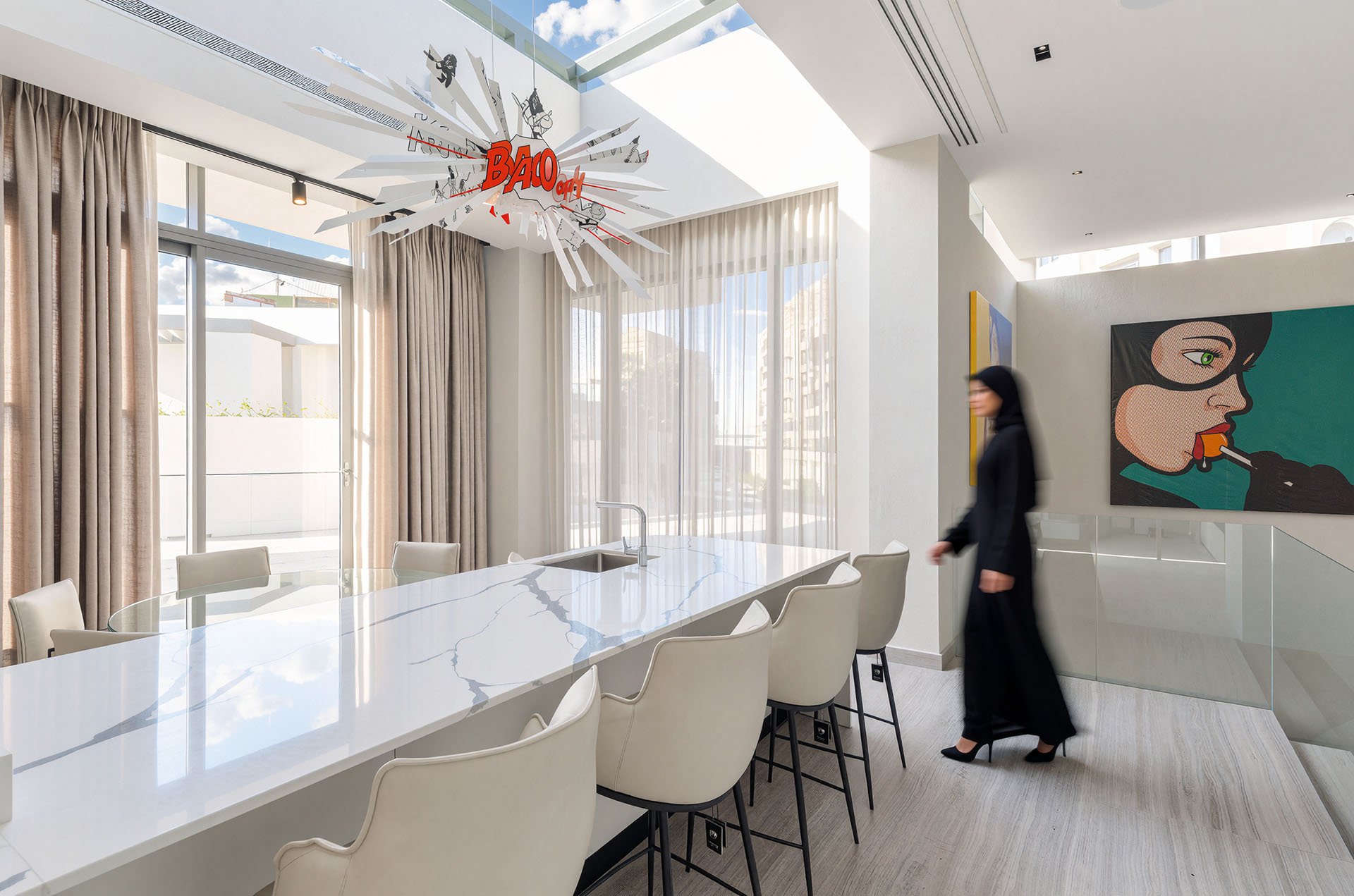 Modern open plan dining room with long marble dining table and statement lighting fixture by Hammad Iqbal