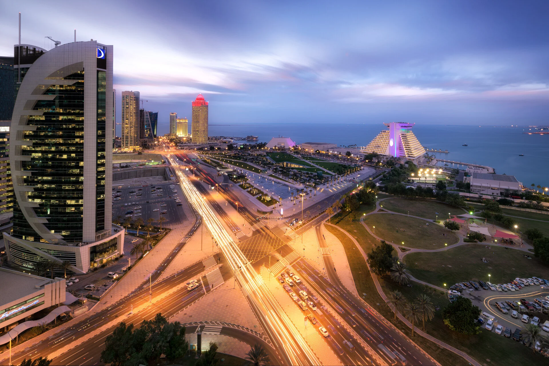 High angle twilight vista showing long exposure traffic trails leading toward the iconic Sheraton Hotel in Doha by Hammad Iqbal