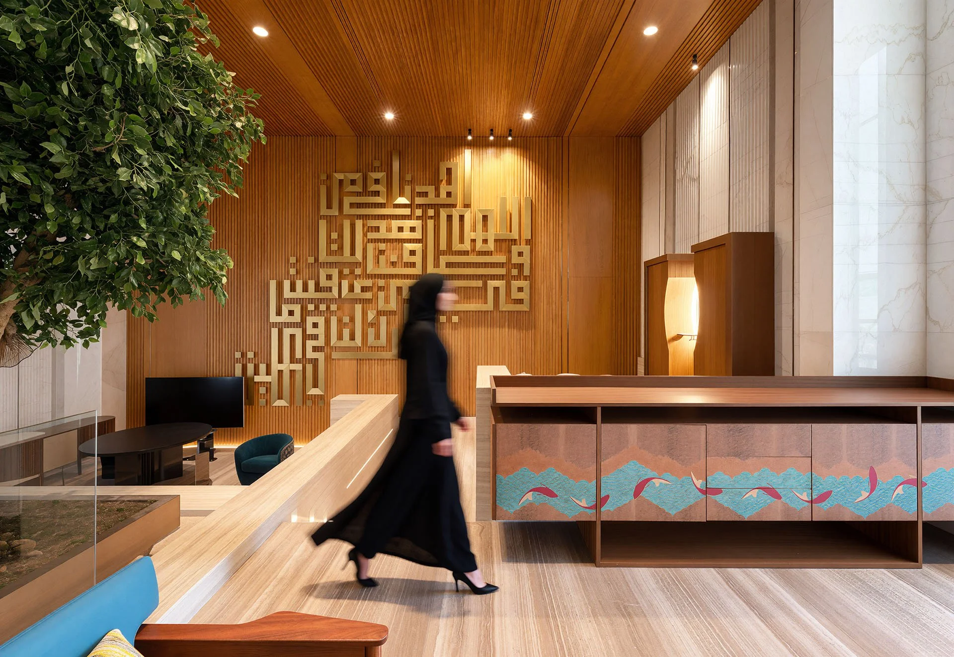 Interior view of warm wood reception lounge with custom Arabic calligraphy wall carving in luxury villa by Hammad Iqbal