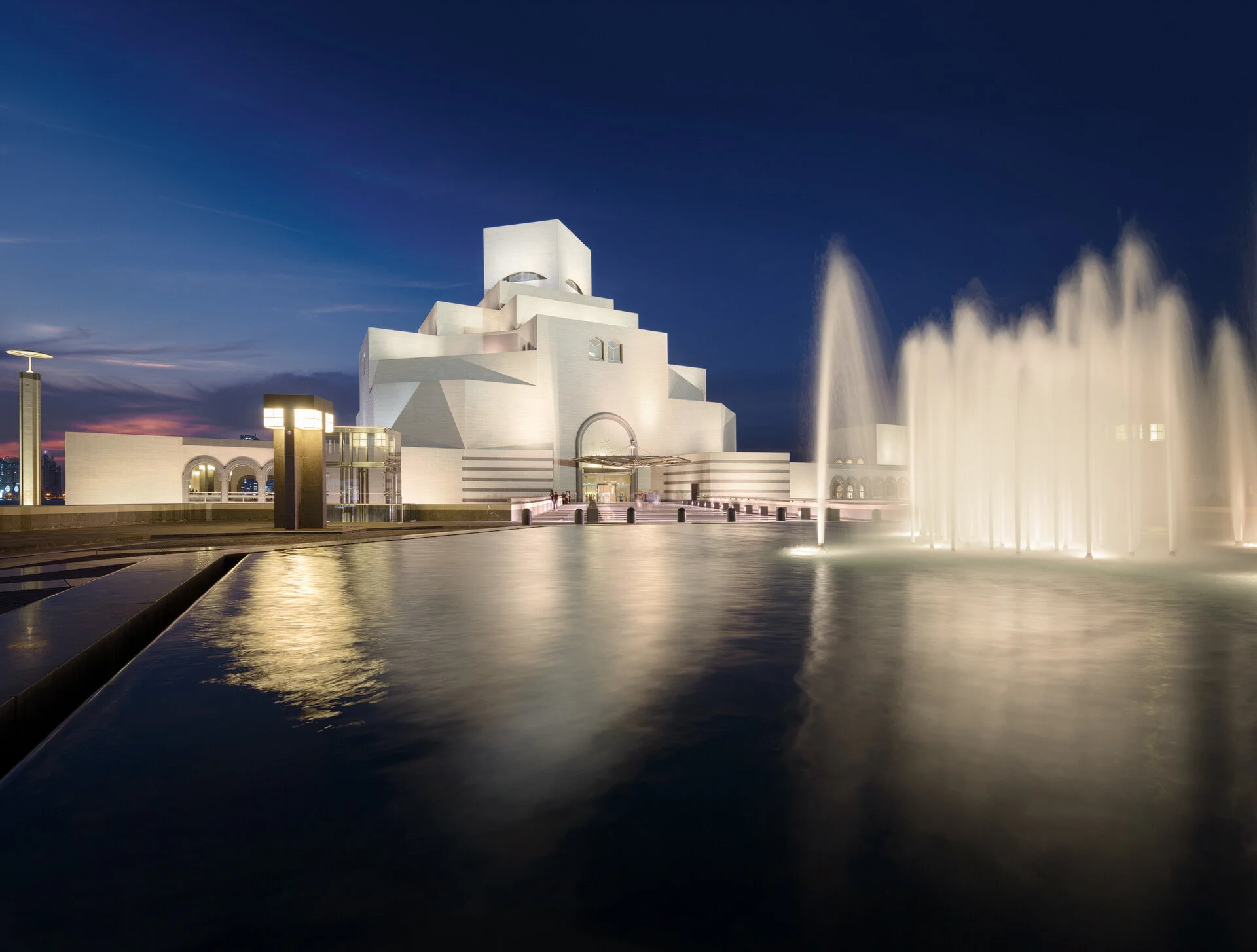 Long exposure blue hour shot of the Museum of Islamic Art exterior featuring foreground water fountain and limestone facade in Doha Qatar by Hammad Iqbal