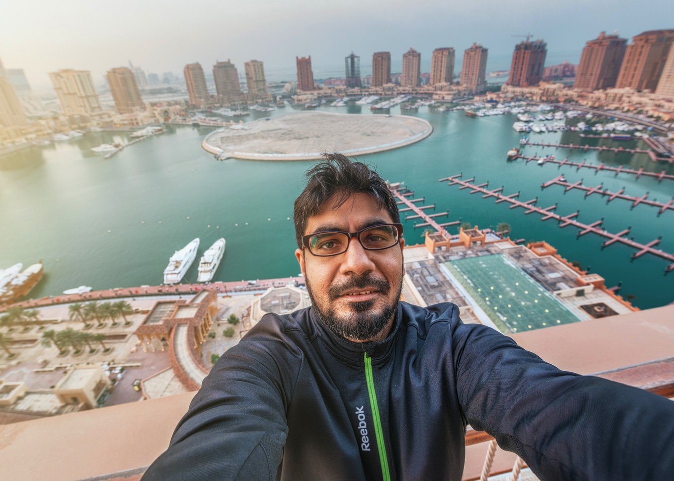 Rooftop selfie of photographer Hammad Iqbal overlooking The Pearl Qatar during an architectural shoot