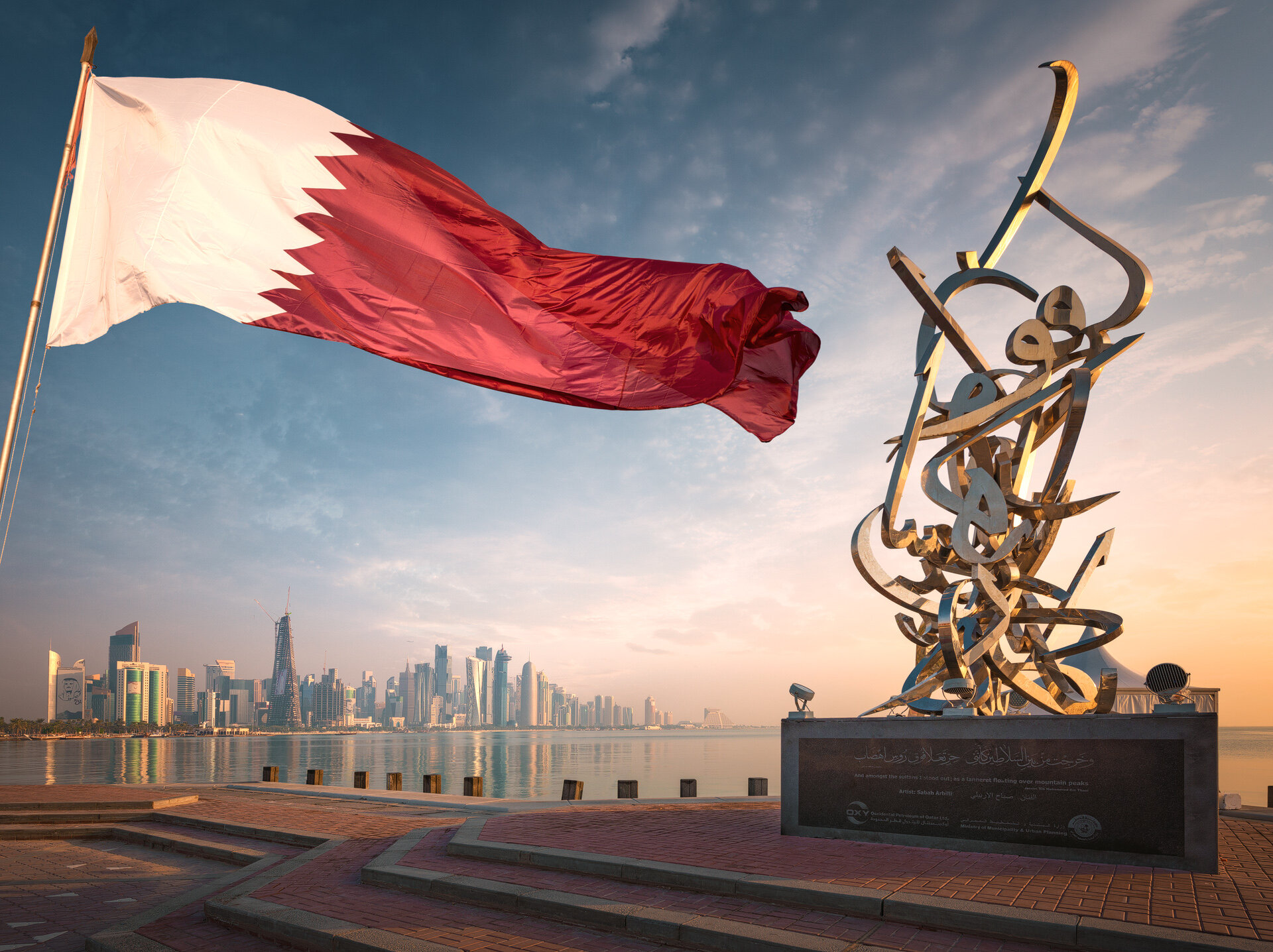 Stainless steel Arabic calligraphy sculpture by artist Sabah Arbilli on the Doha Corniche featuring the Qatari flag and skyline by Hammad Iqbal