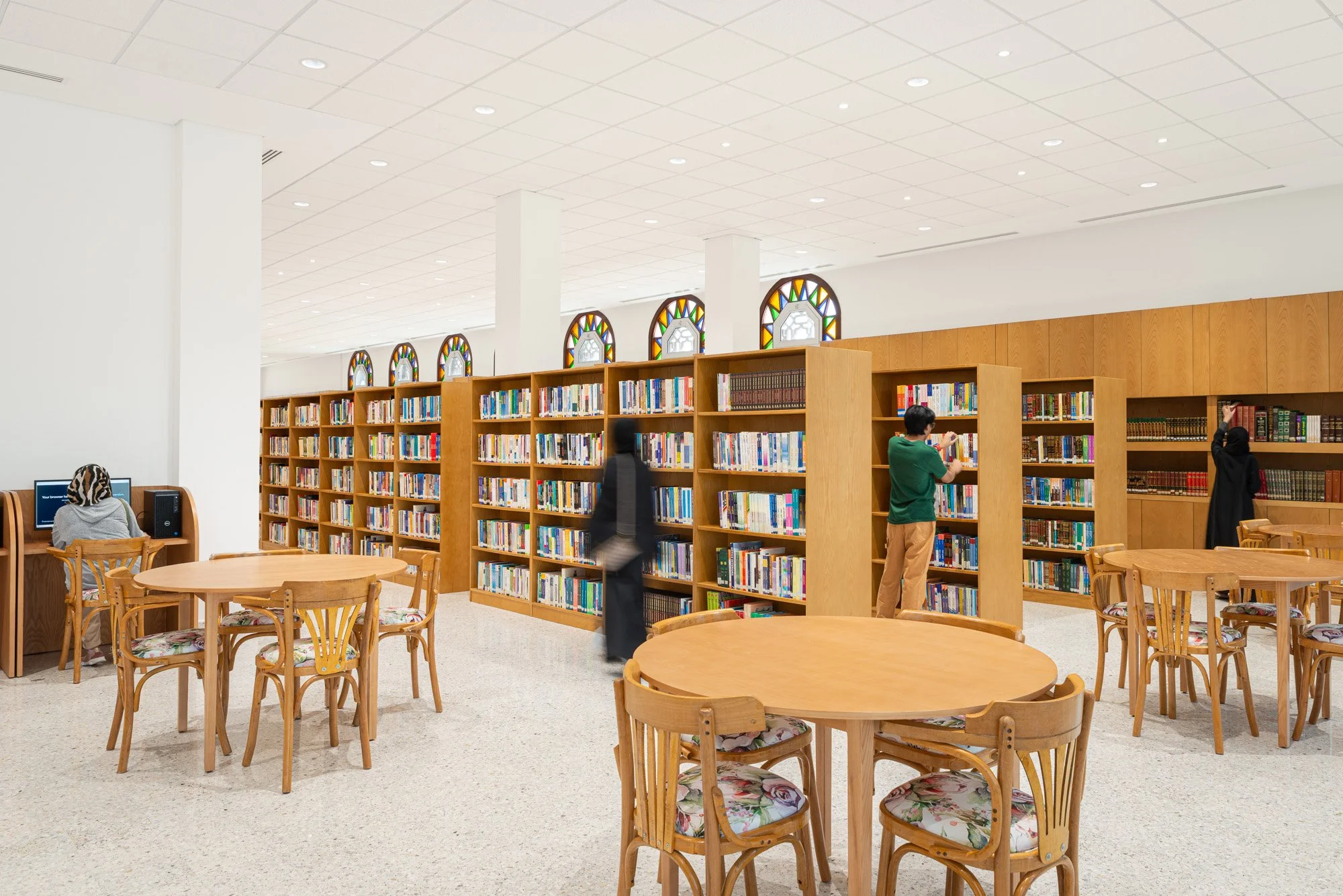 Spacious main reading hall interior at Dar Al Kutub public library in Doha featuring wooden bookshelves, study seating, and stained-glass windows captured by real estate photographer Hammad Iqbal