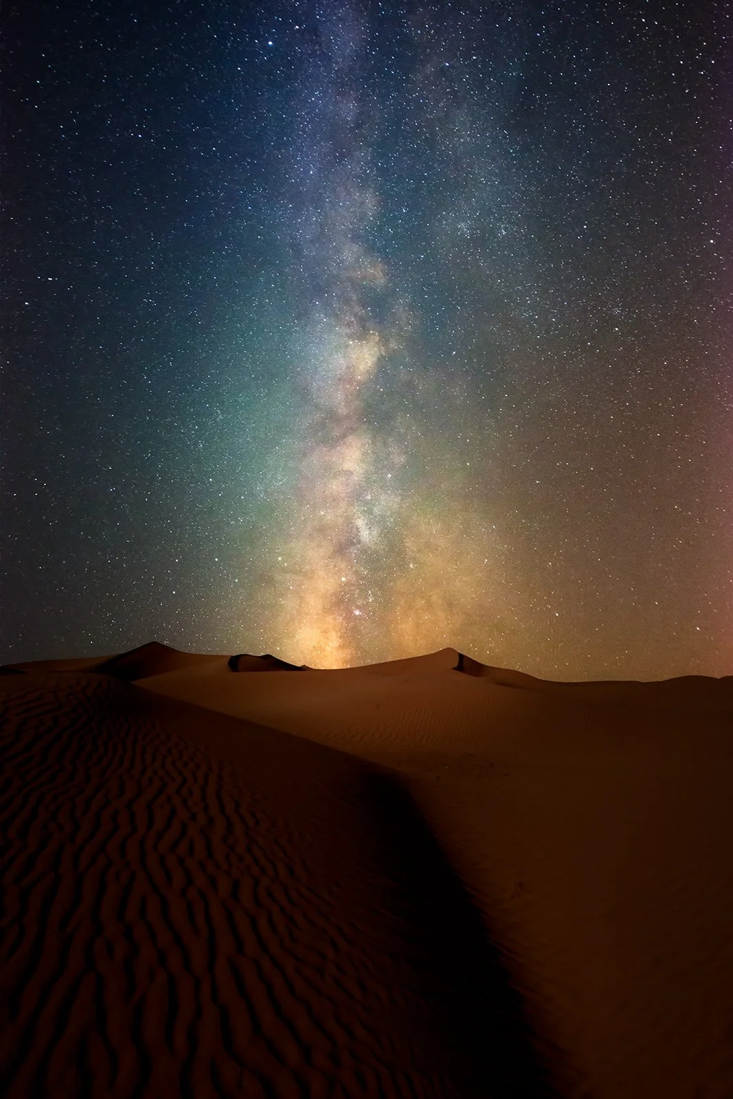 Vertical orientation astrophotography shot of Milky Way galactic core rising directly over desert sand dunes in Qatar by Hammad Iqbal