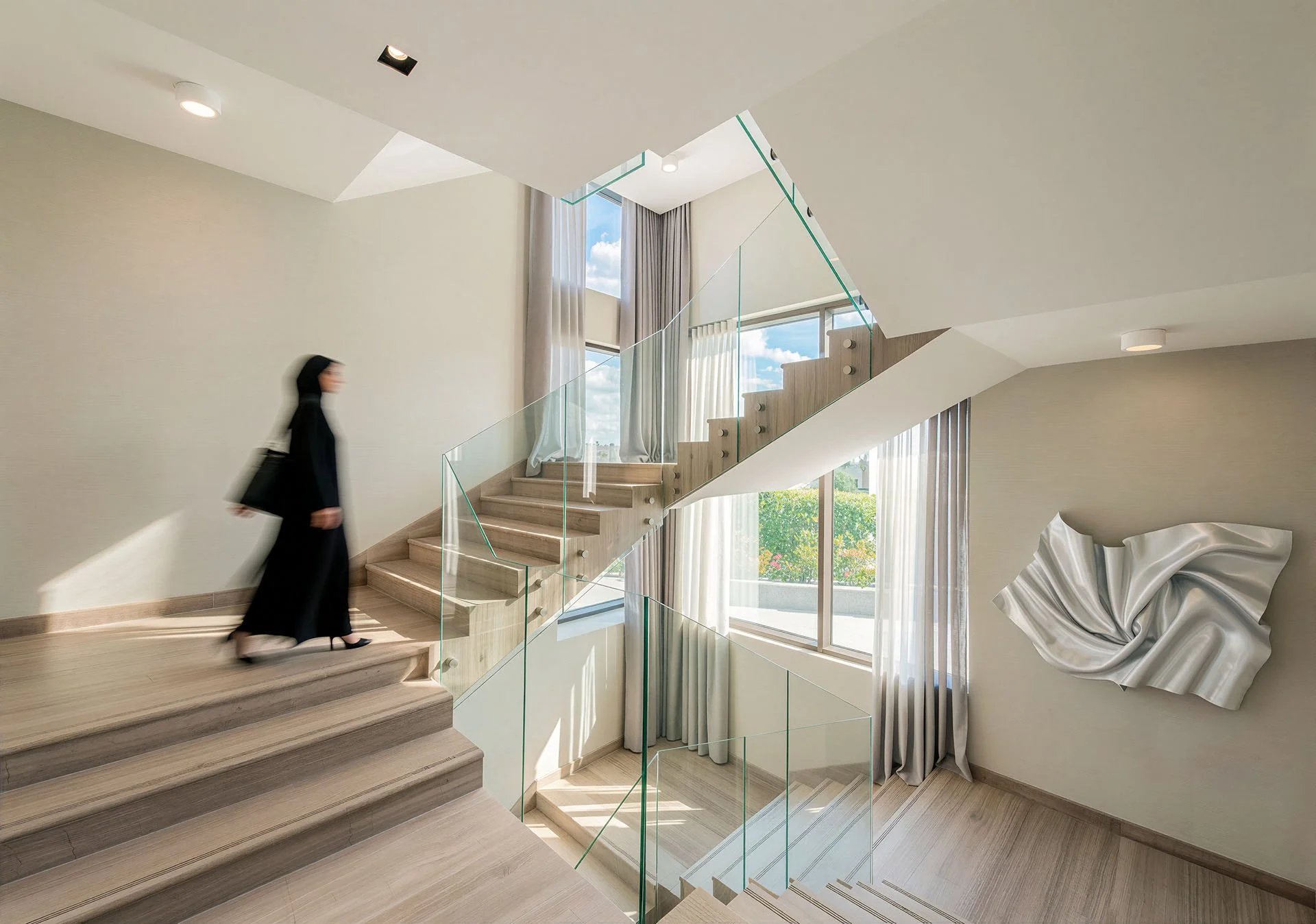 Contemporary floating wooden stairs with glass handrails and sculpture wall in modern Qatari home by Hammad Iqbal