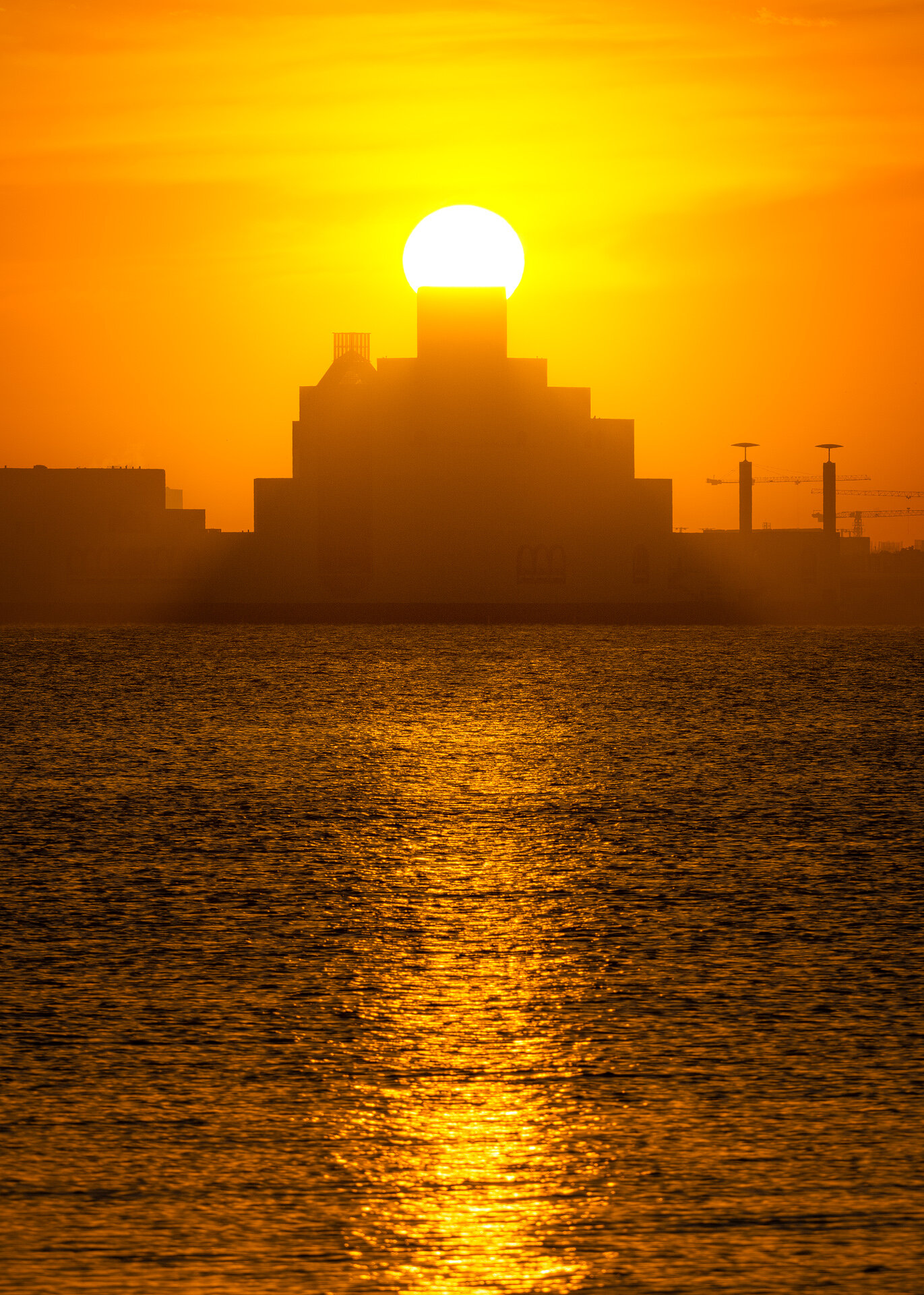 Golden hour sunset silhouette of the Museum of Islamic Art over glowing sea waters in Doha by Hammad Iqbal