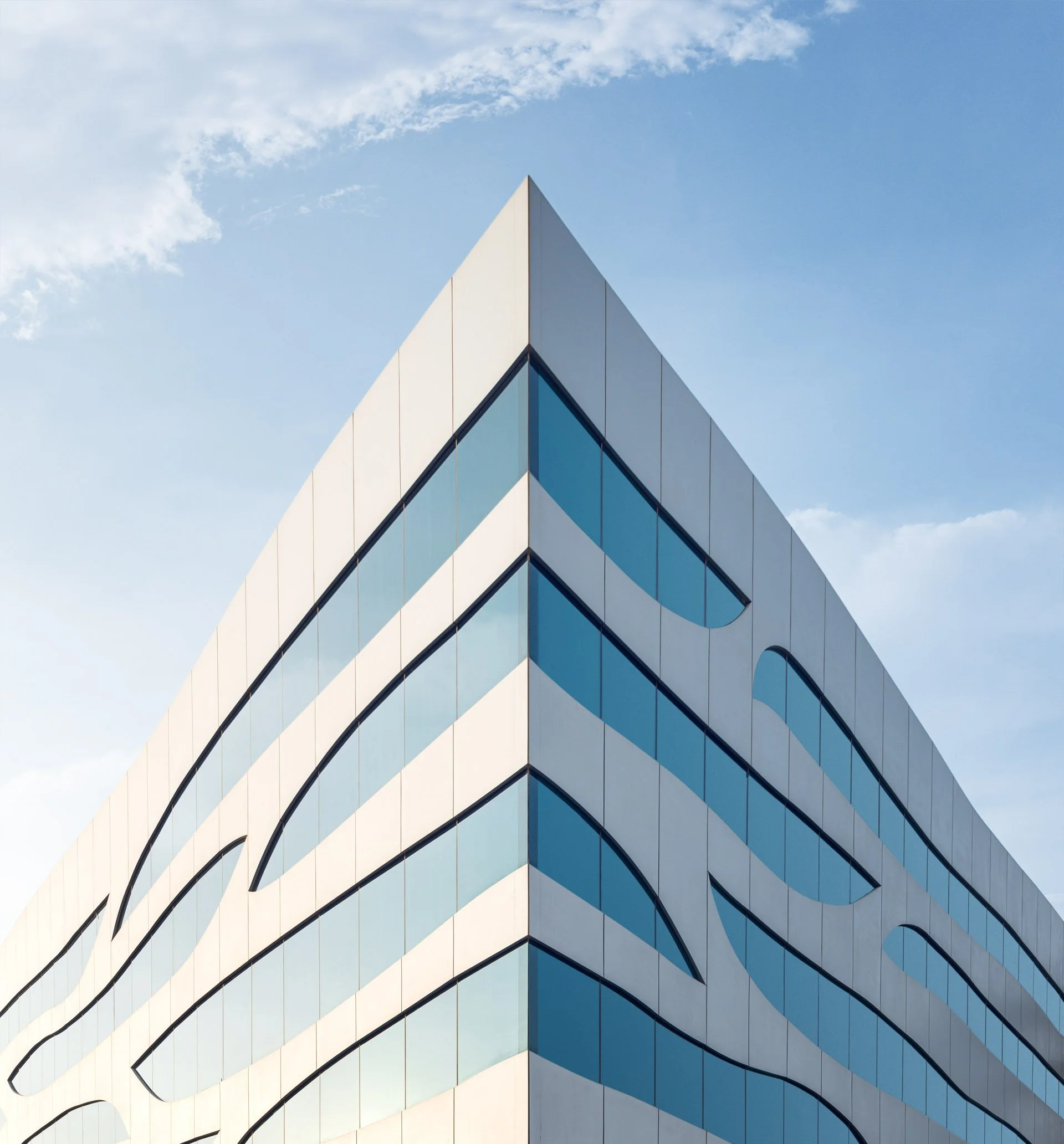 Symmetrical shot of the Aspire foundation headquarters set against a blue sky with some clouds.