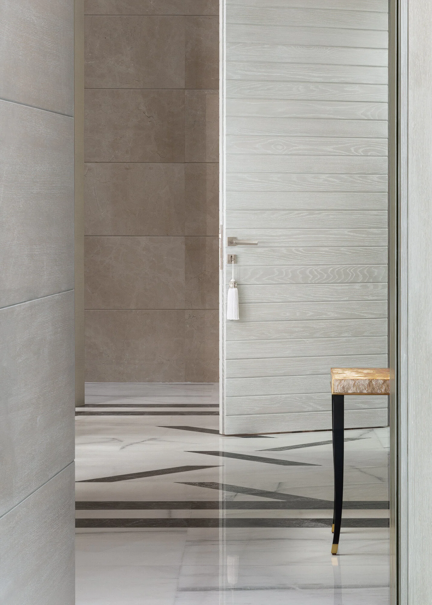 Detail photograph of light wood textured slatted door brass handle and travertine wall cladding in a luxury Qatar villa by Hammad Iqbal