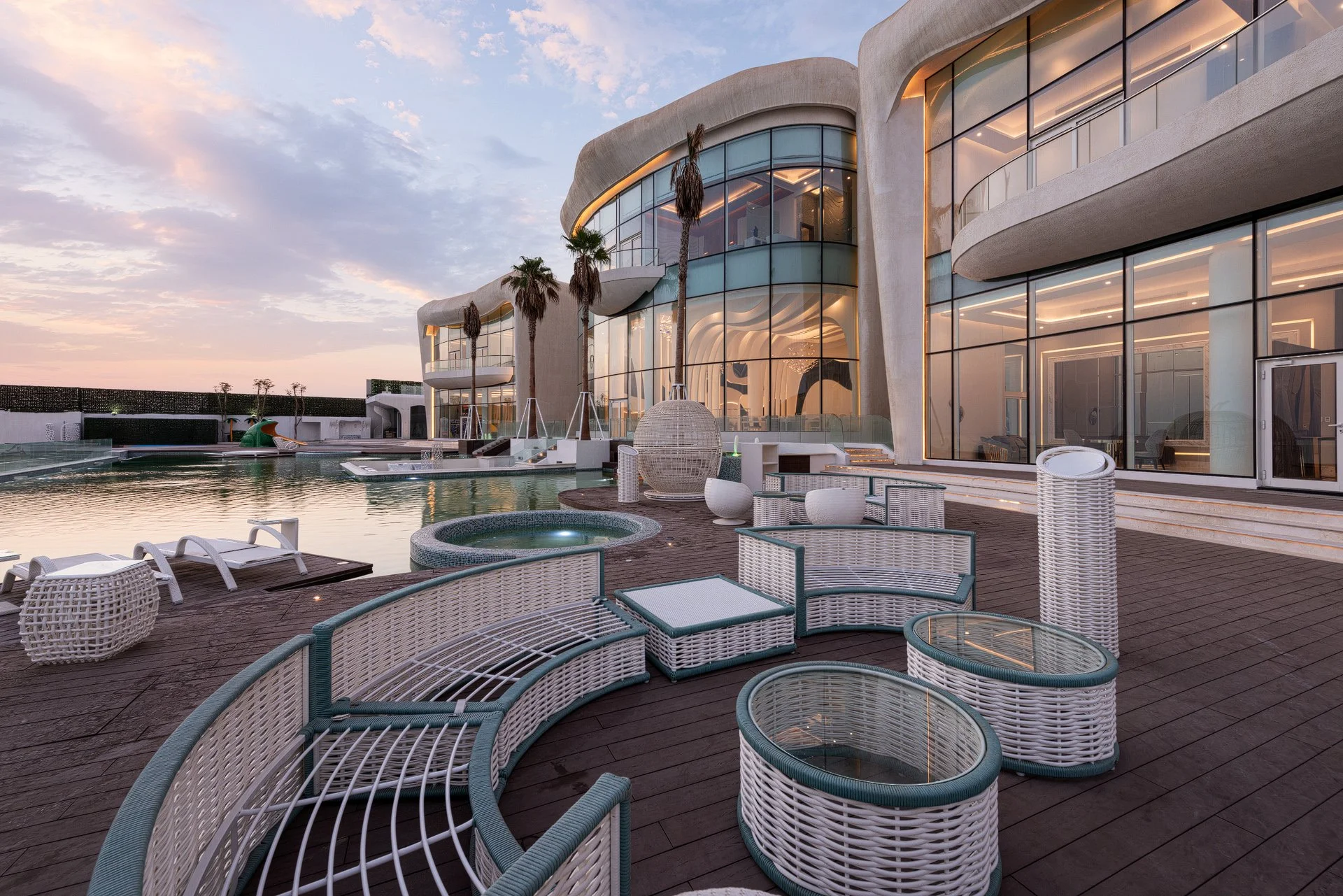Rear pool terrace with woven outdoor seating and double height glass facade overlooking the ocean in Qatar by Hammad Iqbal