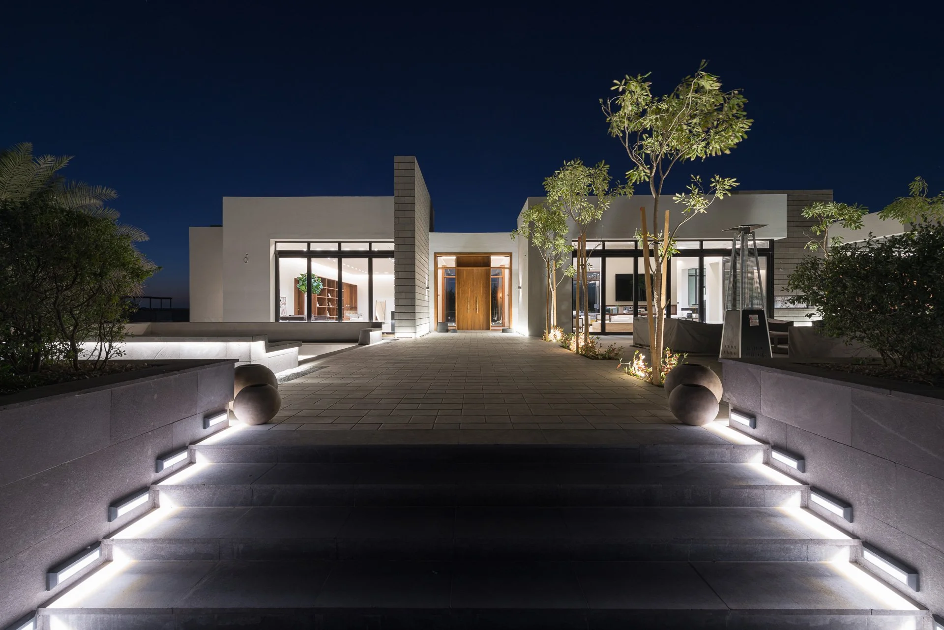 Night architectural photograph of illuminated stone terrace steps and modern pavilion facade in Qatar by Hammad Iqbal