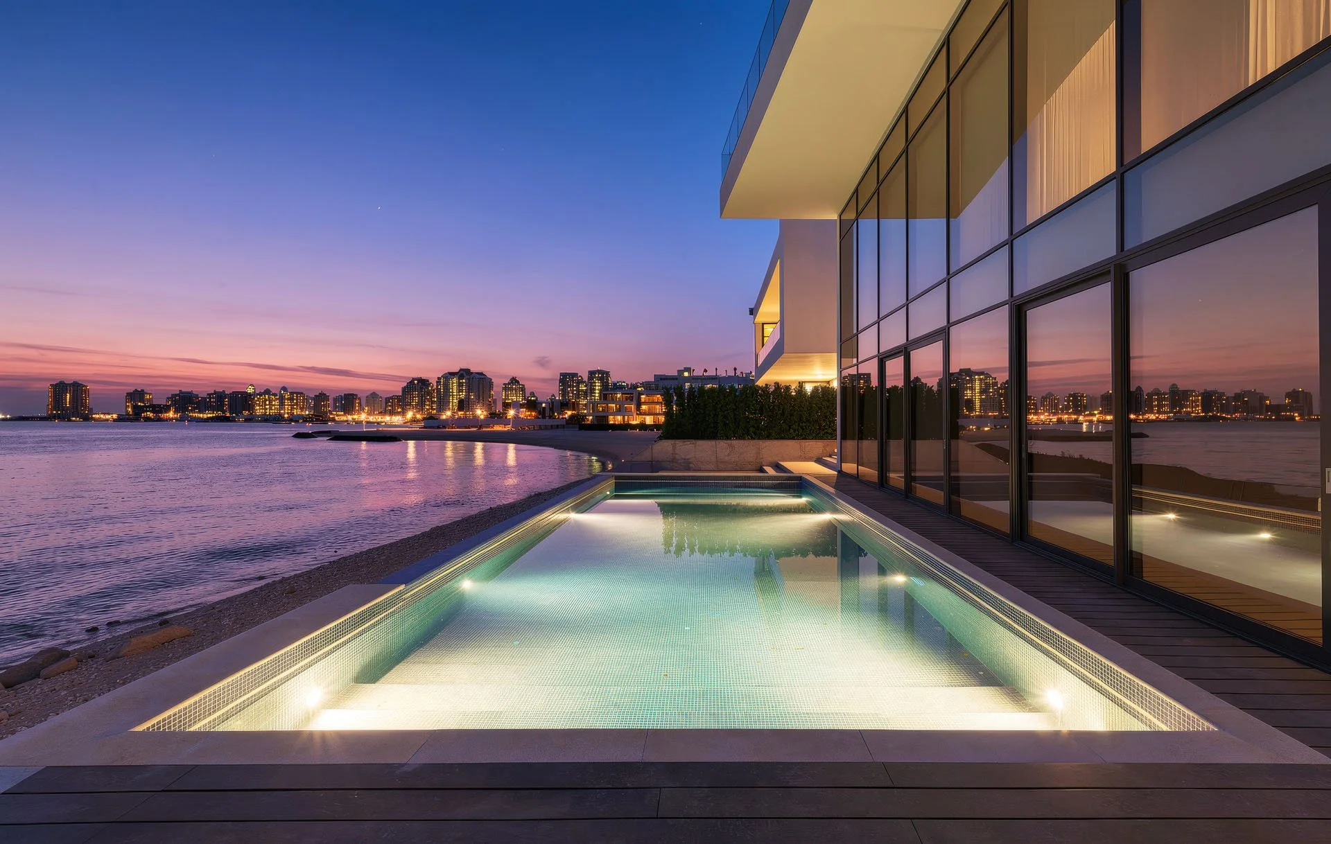 Sunset architectural photo of illuminated infinity swimming pool connecting to beach at The Pearl Qatar by Hammad Iqbal