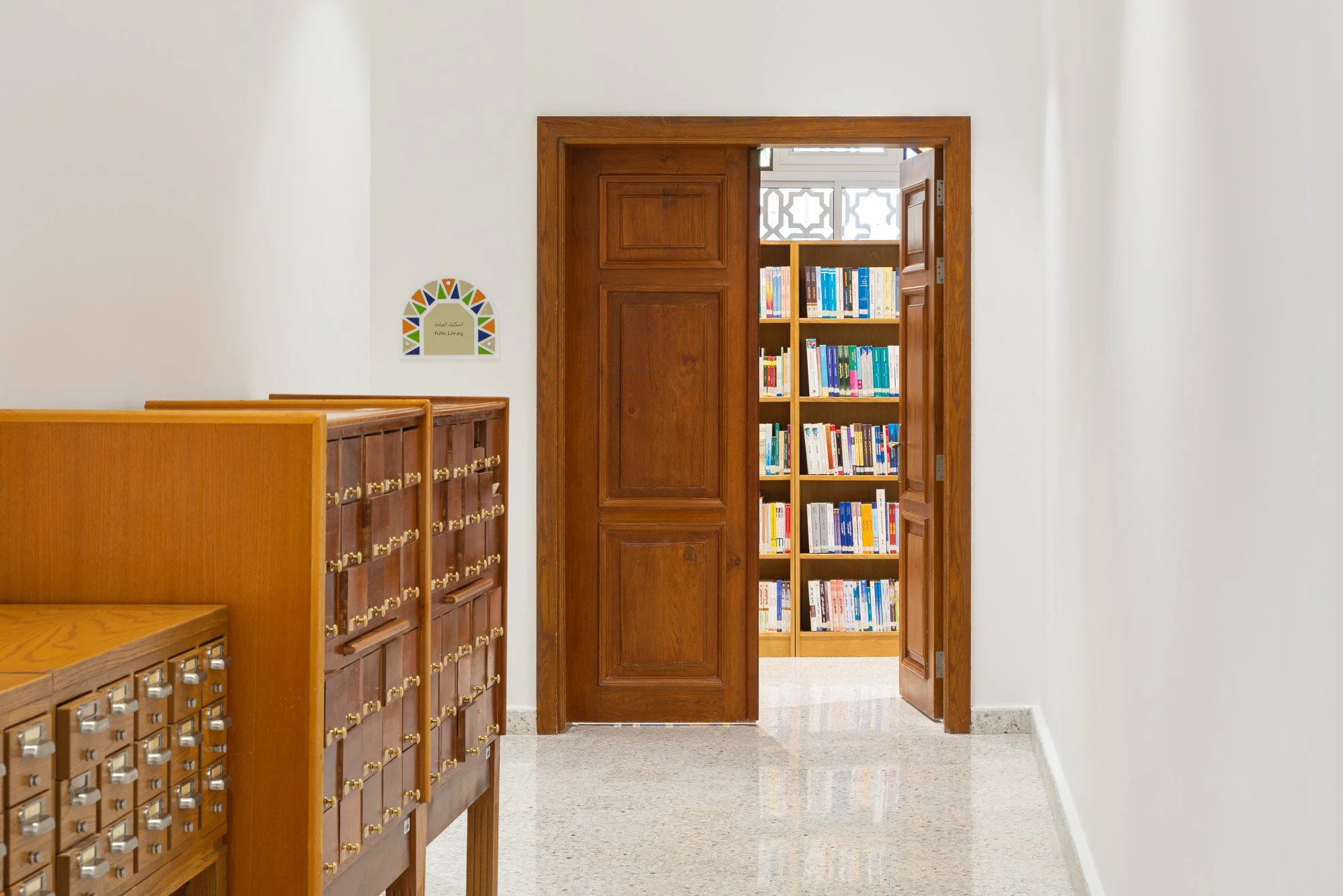 Corridor with vintage wooden card catalog cabinets leading into main reading hall at Dar Al Kutub public library in Doha shot by architectural photographer Hammad Iqbal
