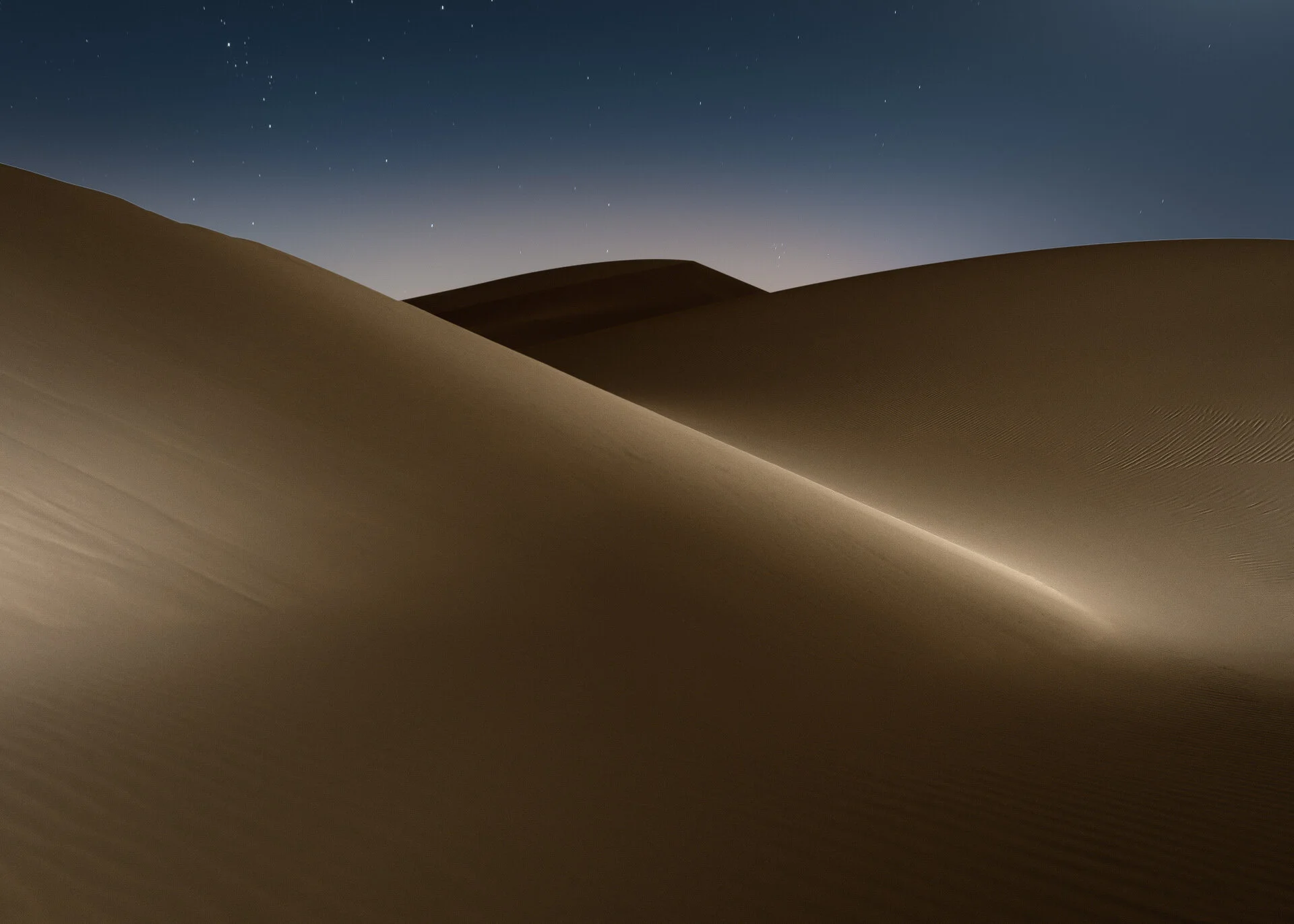 Contoured dune ridge showing high contrast light and shadow in the Qatari desert at night by Hammad Iqbal