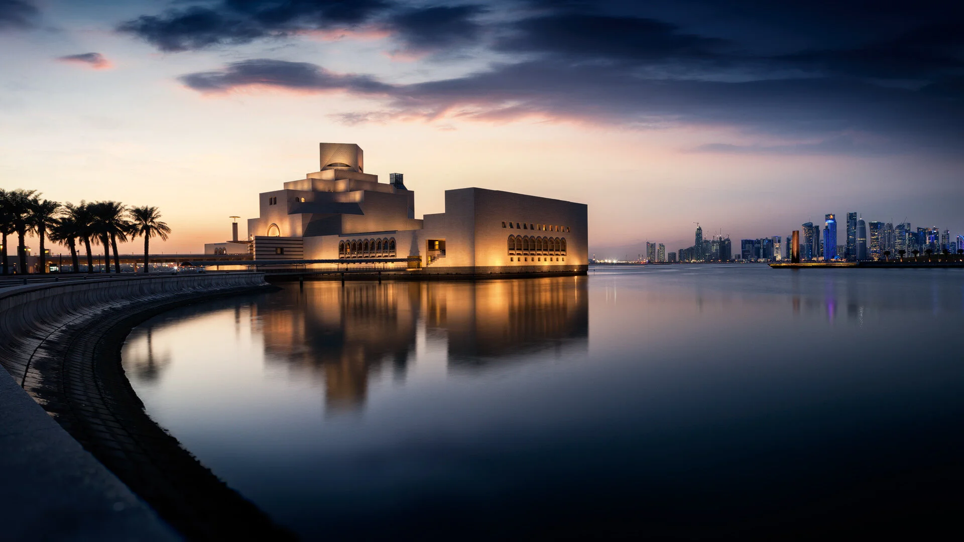 Panoramic long exposure photo of the Museum of Islamic Art at sunset with water reflections and West Bay skyline captured by architectural photographer Hammad Iqbal in Doha Qatar