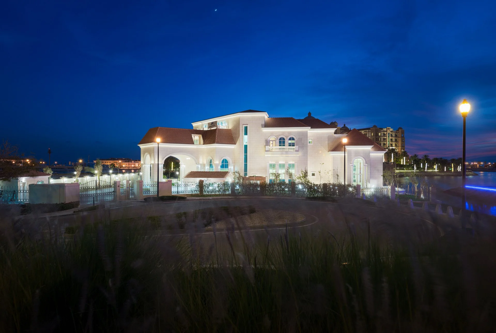 Wide night exterior photo of an illuminated luxury waterfront palace facade at The Pearl Qatar photographed by Hammad Iqbal