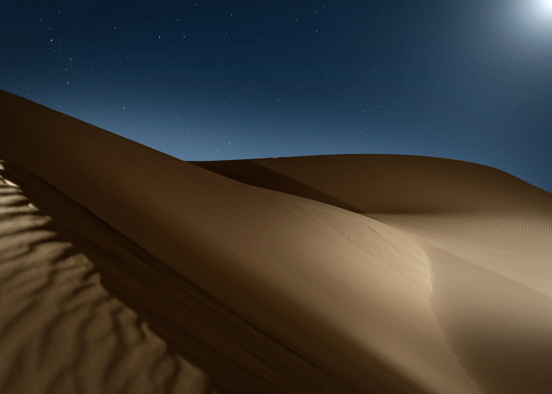 Dramatic diagonal dune ridge illuminated by off-camera flash against dark nocturnal sky in Qatar by Hammad Iqbal