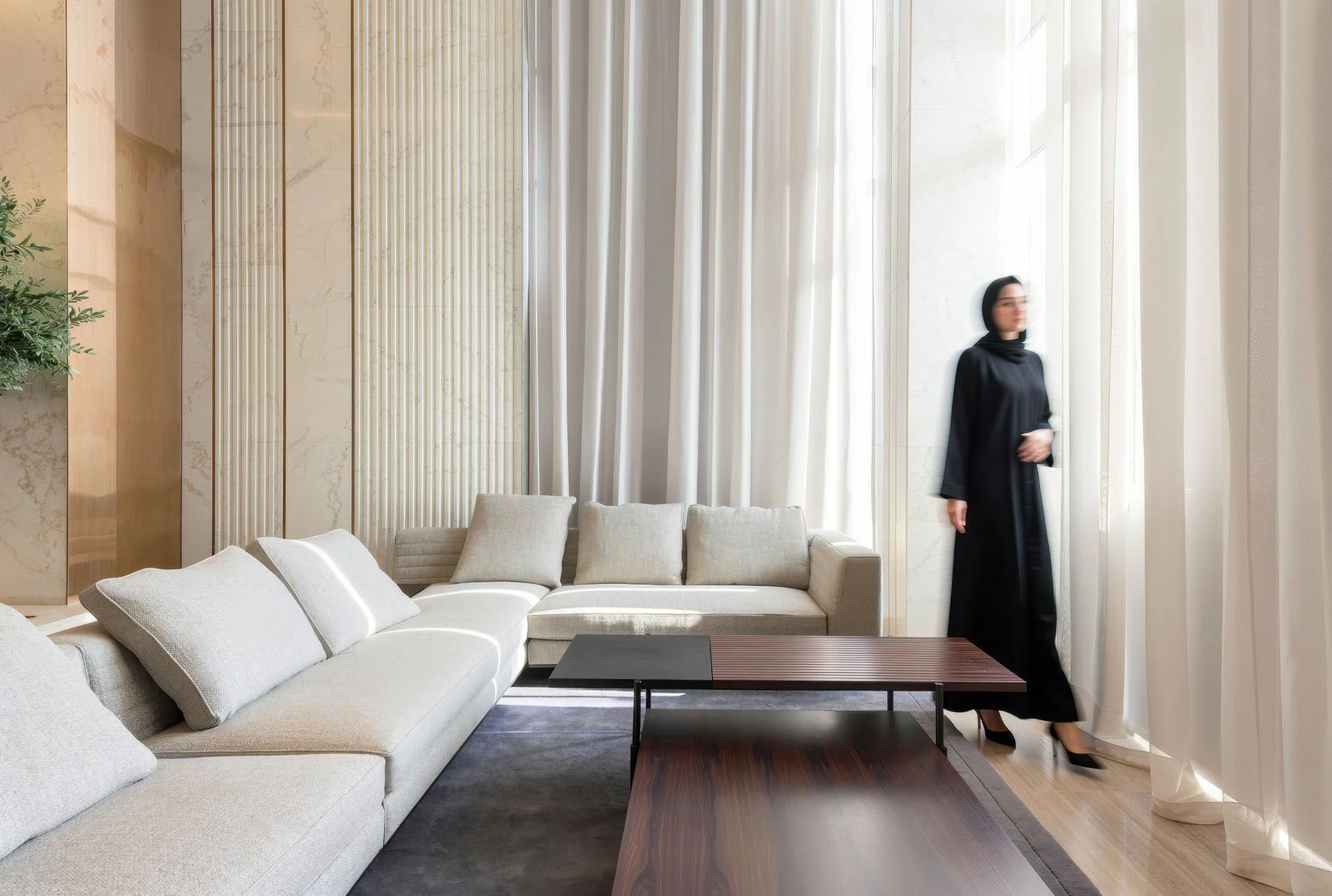 Architectural interior shot of a sunlit luxury living room featuring fluted marble wall panels, sheer floor-to-ceiling drapes, and an off-white sectional sofa in a villa at The Pearl Qatar by Hammad Iqbal