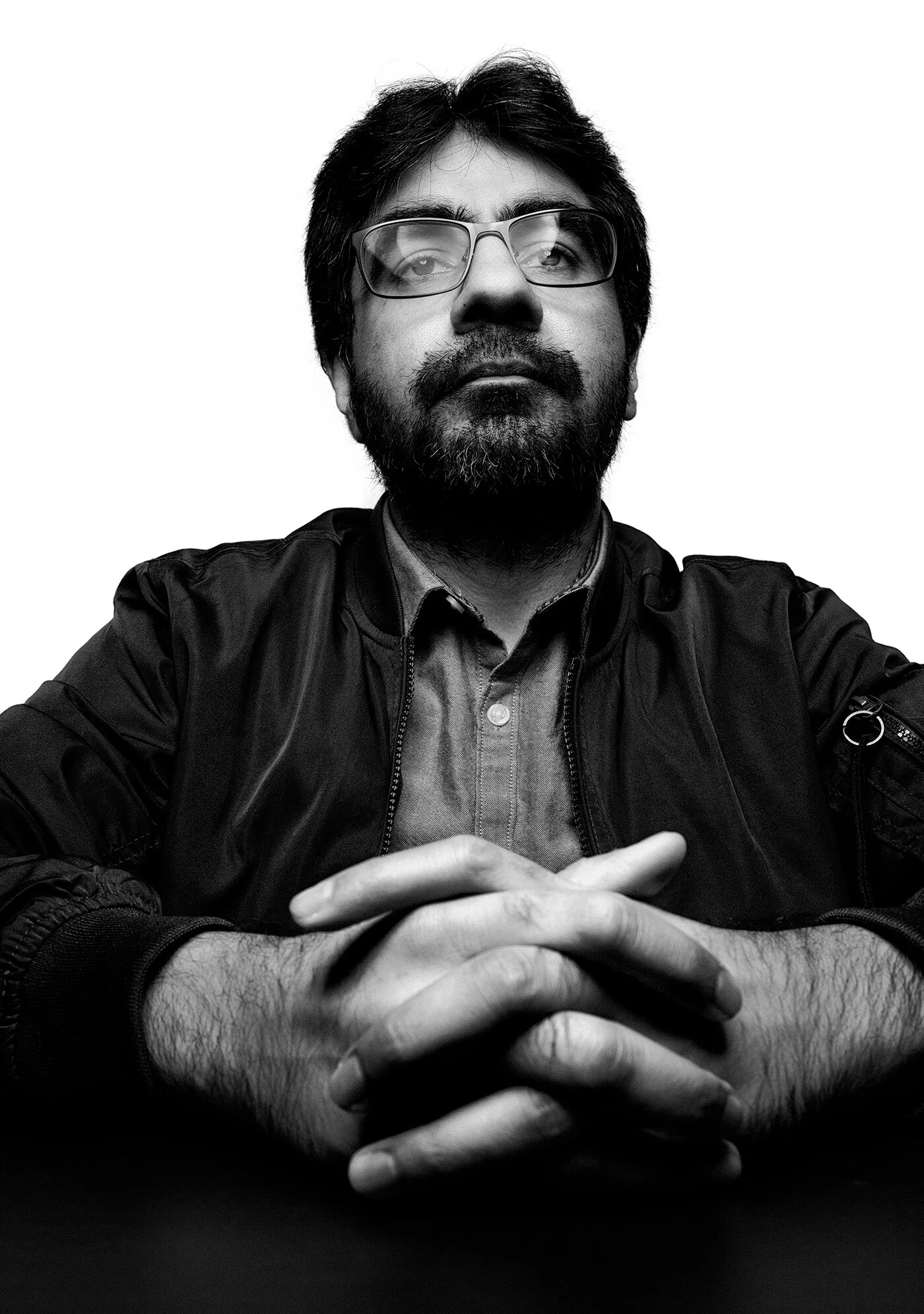 High contrast self portrait with glasses and clasped hands titled Le Professor by Hammad Iqbal
