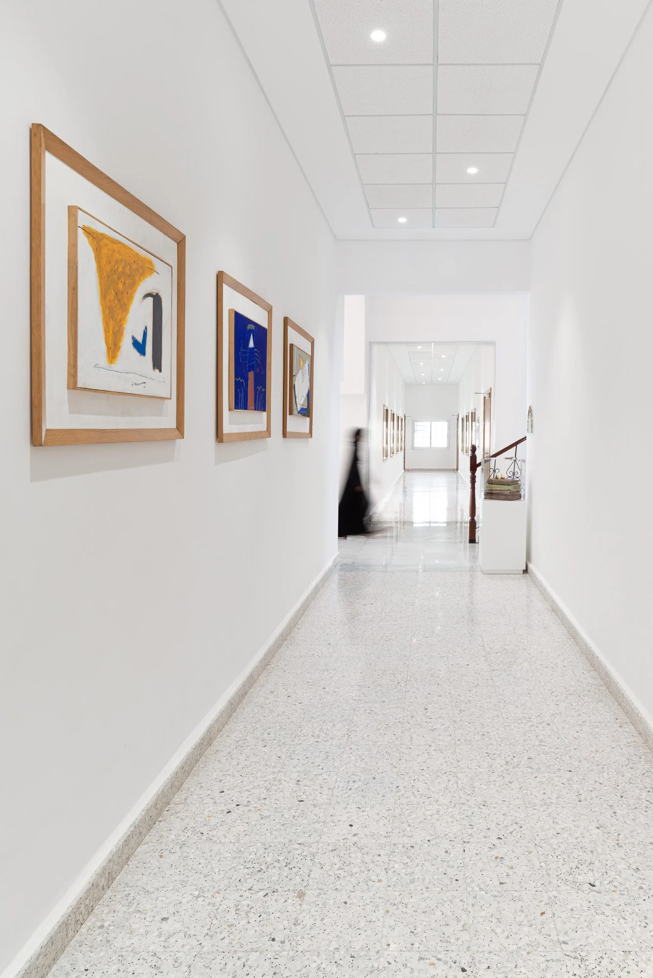 Bright interior corridor with framed art leading to main reading hall stairwell at Dar Al Kutub public library in Doha Qatar captured by architectural photographer Hammad Iqbal
