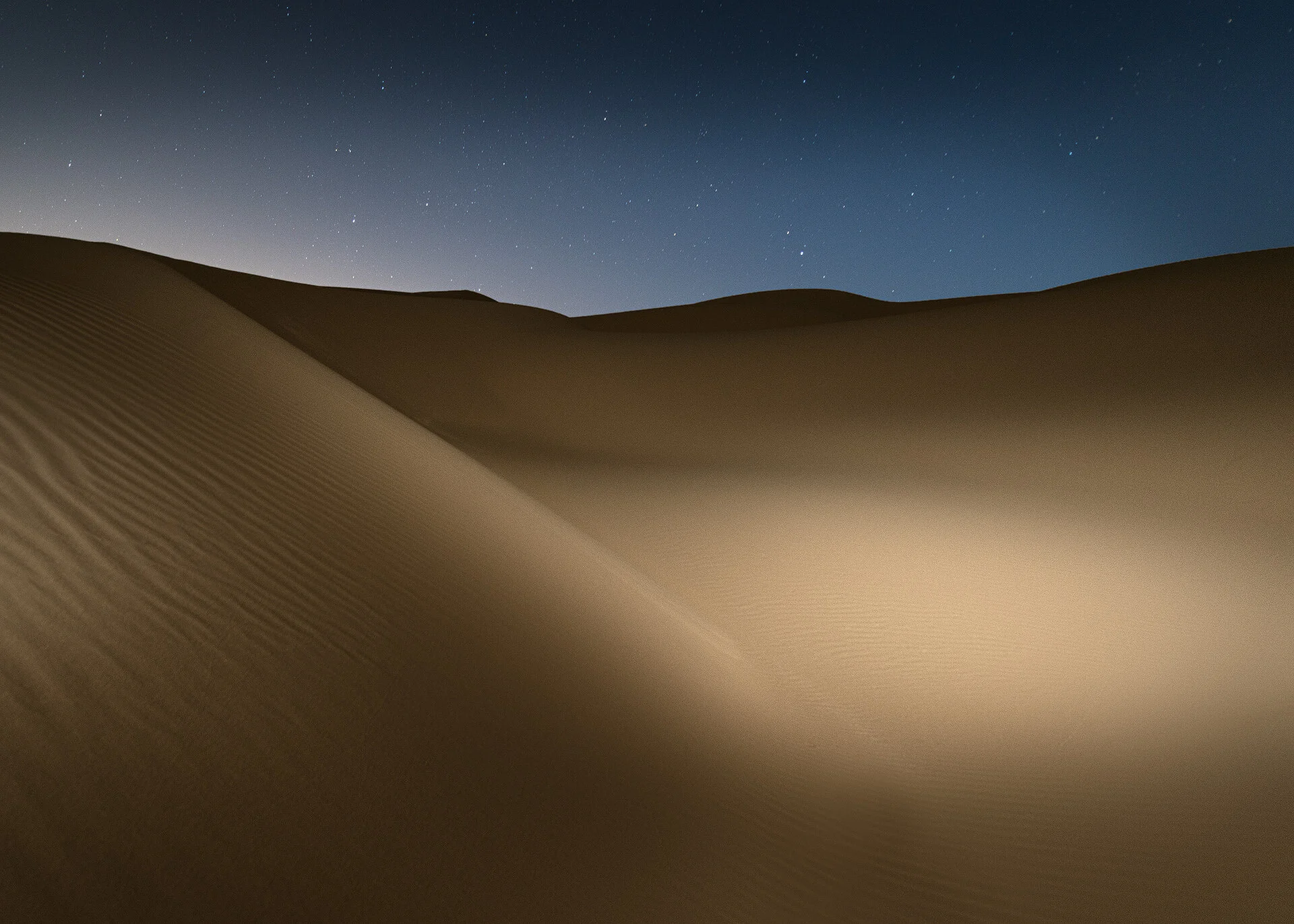 Broad sand dune face lit by side strobe lighting under starlit night sky in Qatar by Hammad Iqbal