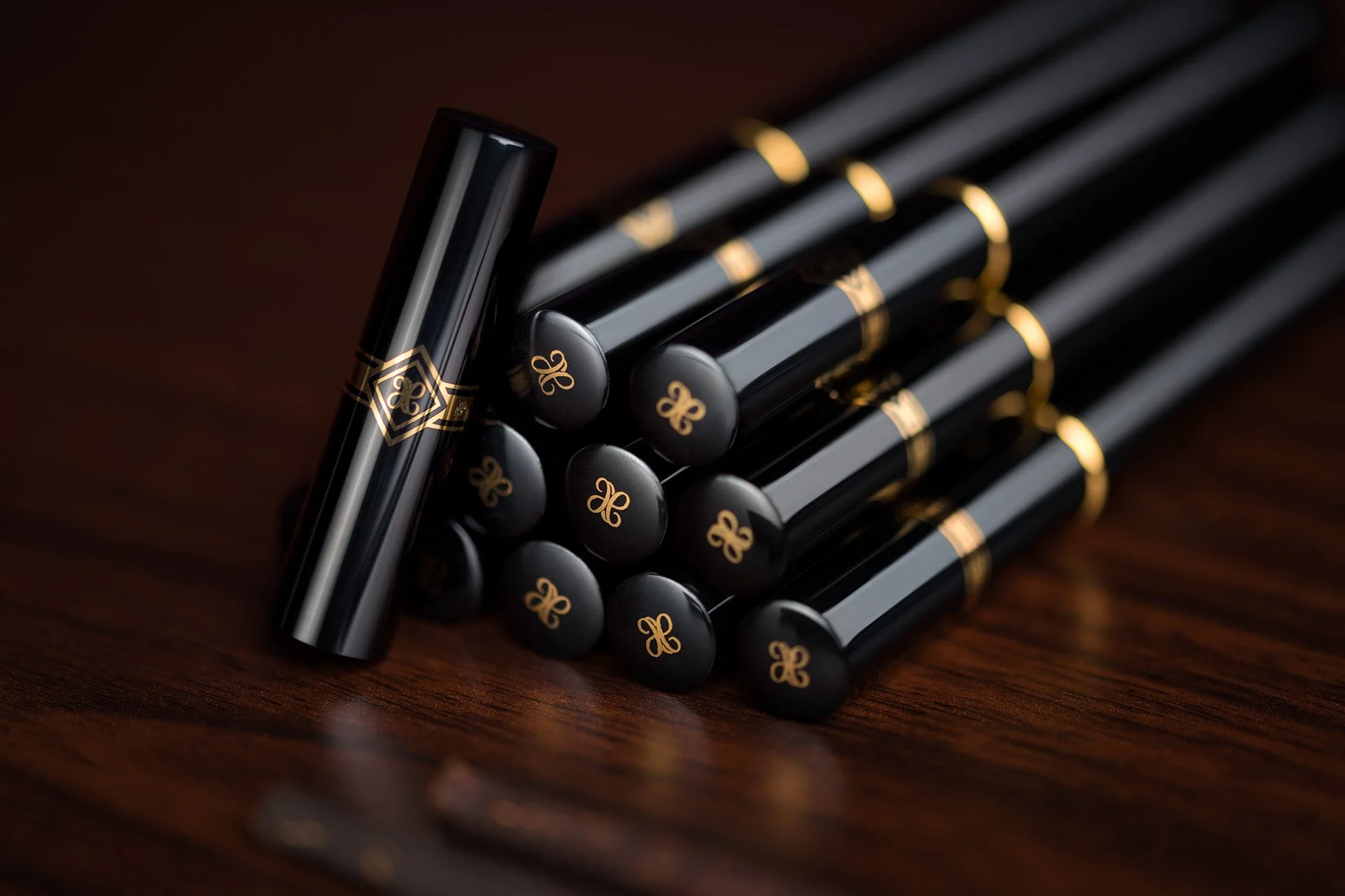 Commercial product photography showing a pyramid stack of black Miswak Royale cases featuring gold engraved monograms by Hammad Iqbal