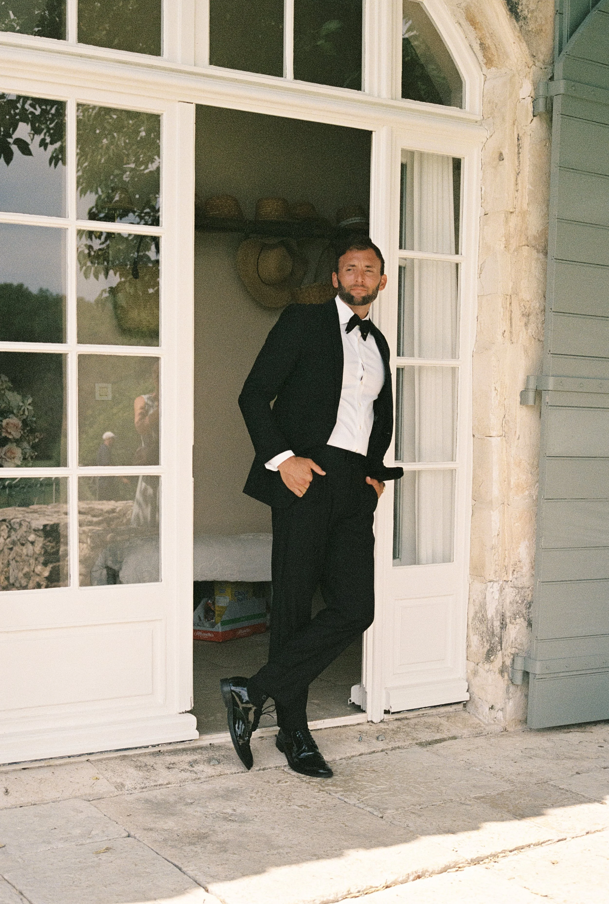 Man in tuxedo standing in doorway of a house.