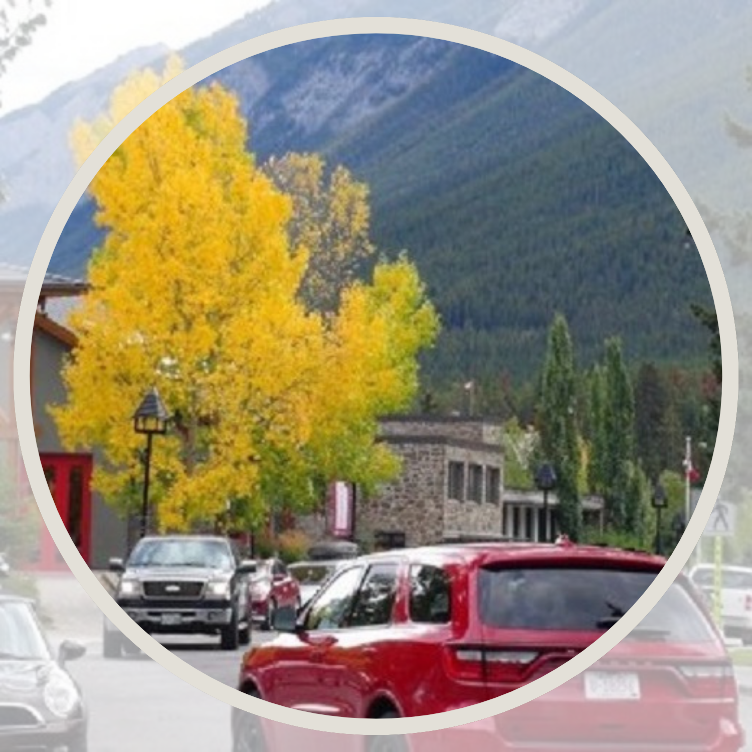 Golden trees and small-town car traffic, with mountains in the background