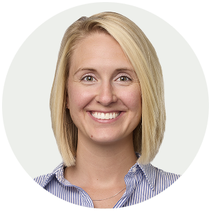A woman with blonde hair smiling, wearing a blue and white striped shirt.