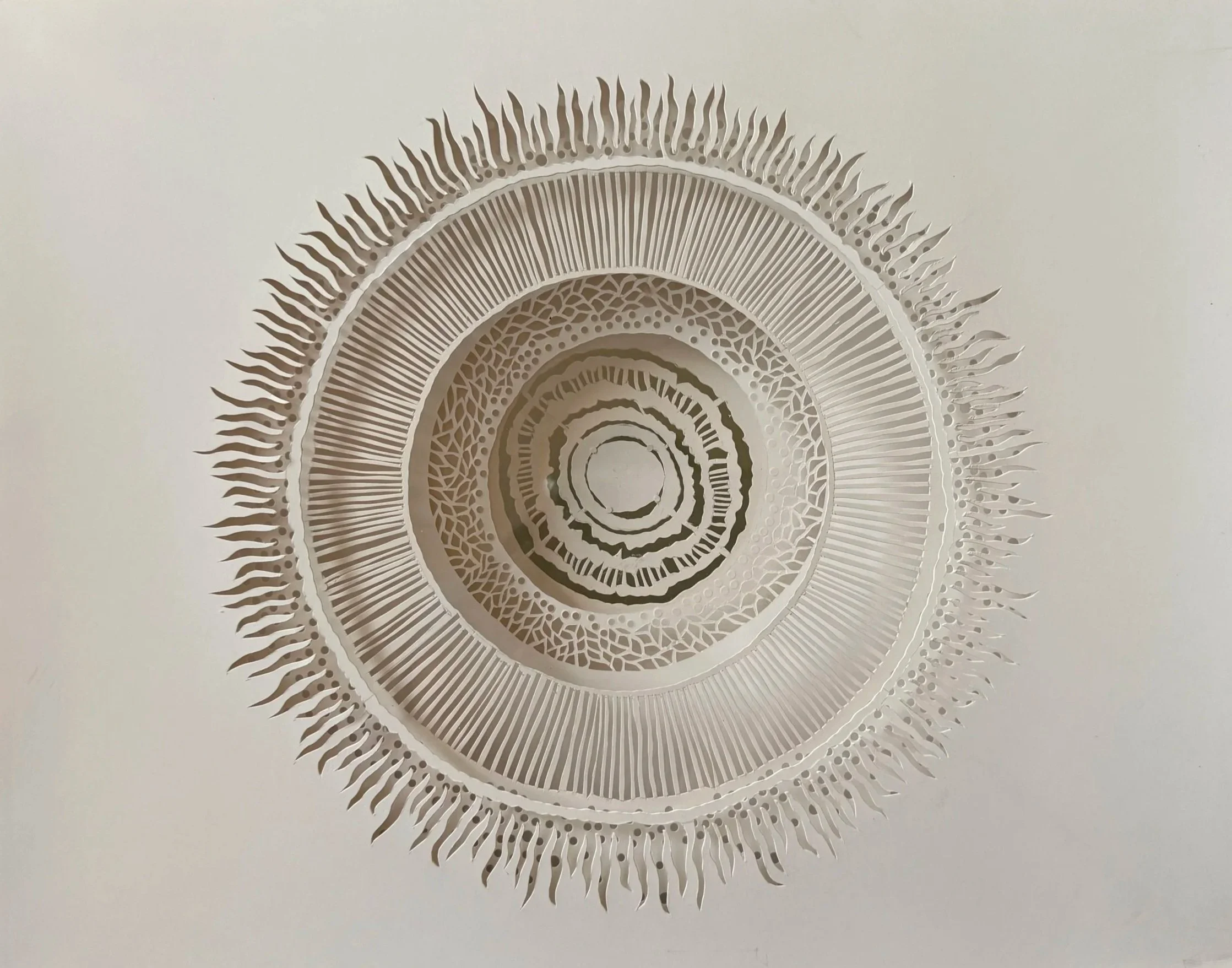 Decorative circular wall art with intricate patterns and a layered design, featuring radiating lines and flame-like protrusions.