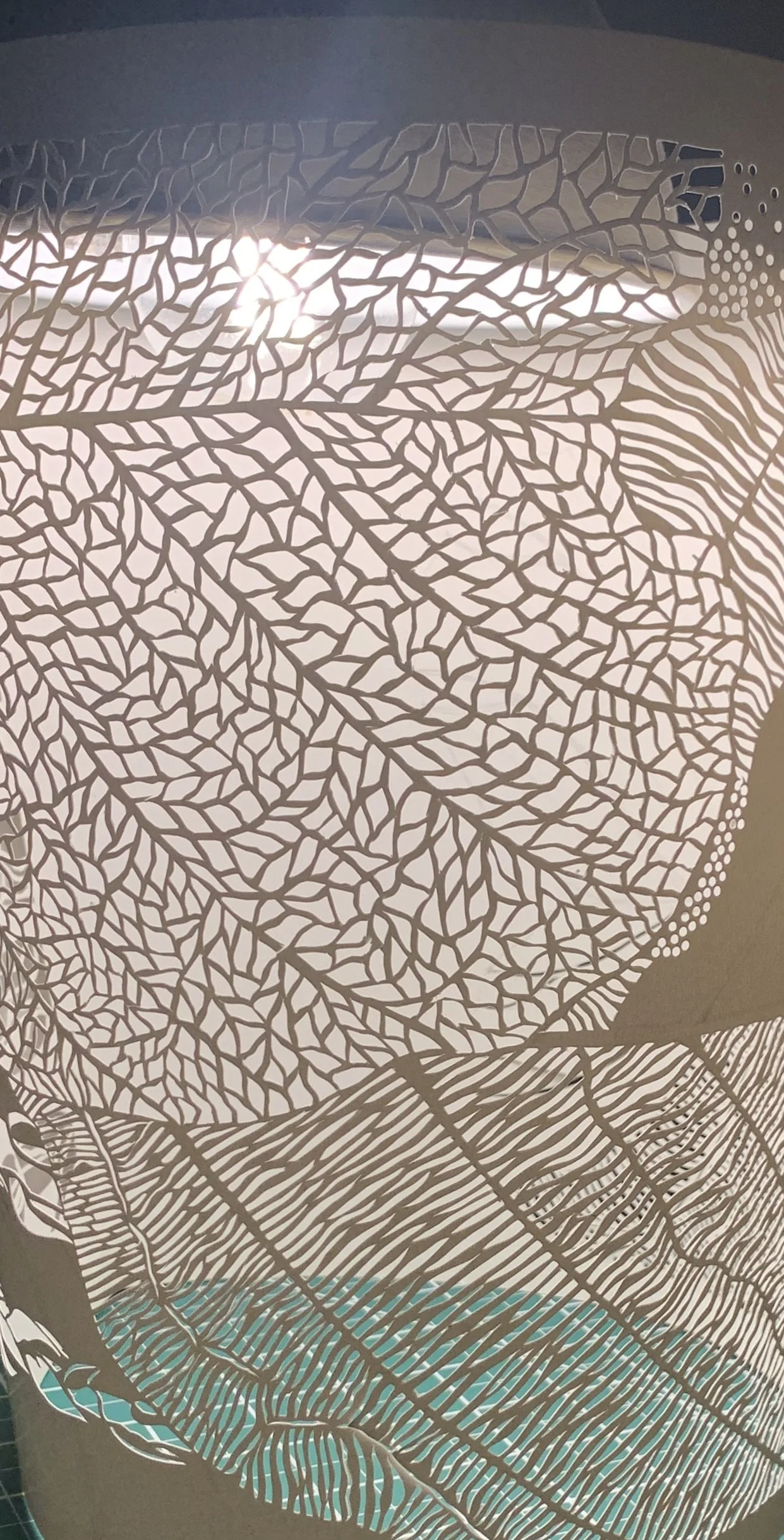 Close-up of a decorative lamp with intricate leaf and branch patterns, with light shining through the cutouts.
