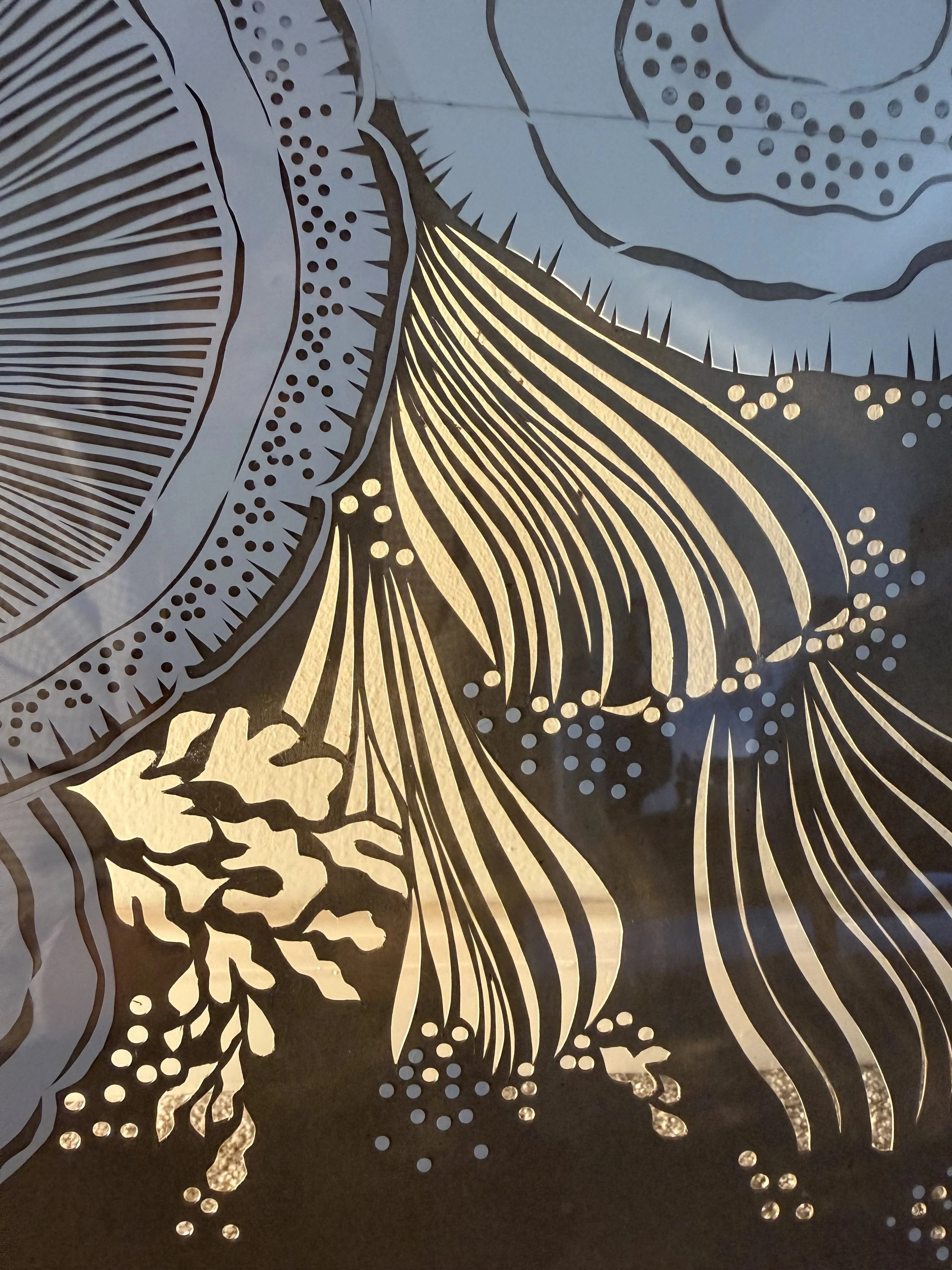 Close-up of intricately cut  paper featuring detailed textural leaf patterns that allow light to shine through.