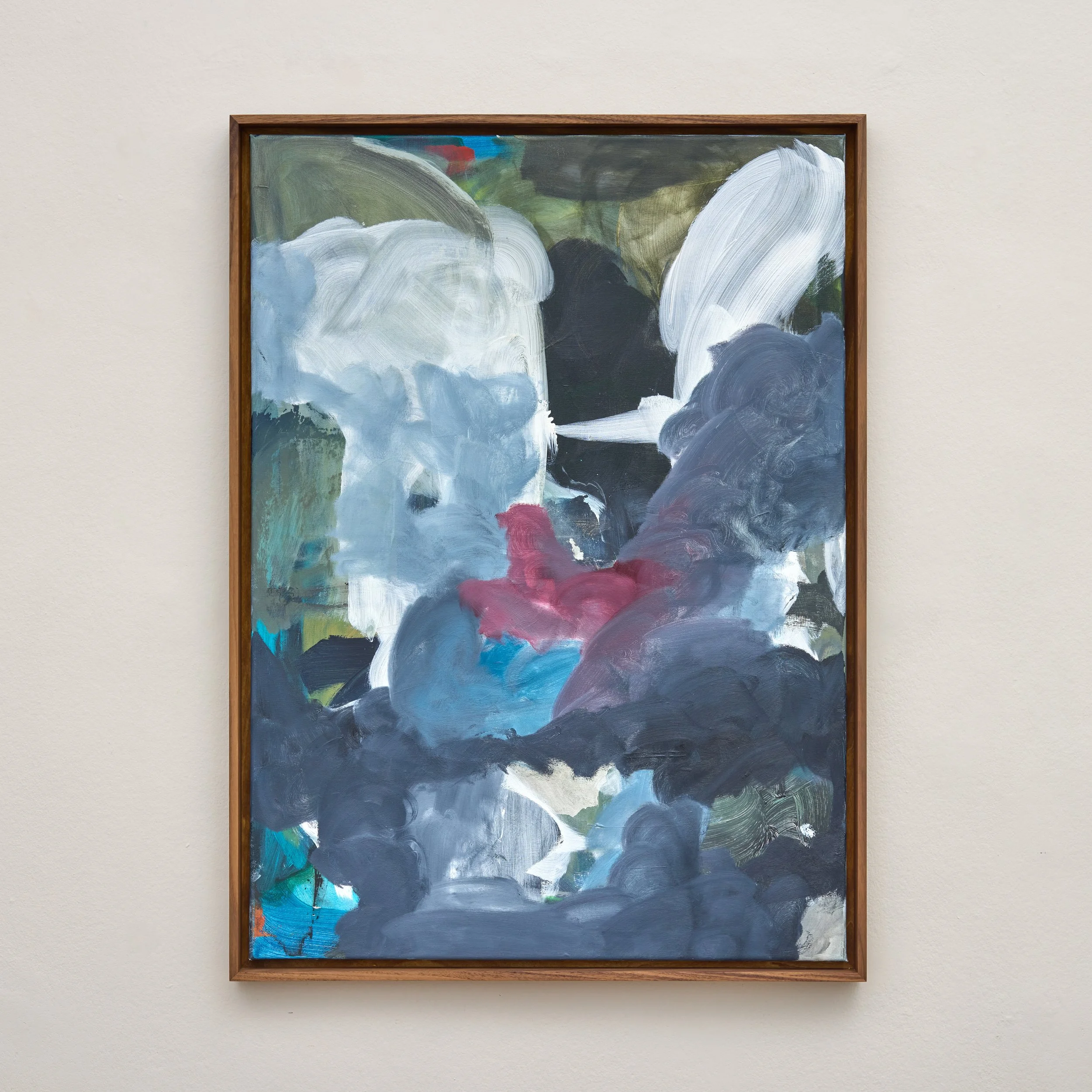 An abstract painting with large, swirling brushstrokes in shades of white, black, green, blue, and red, framed with a wooden border, hanging on a plain, beige wall.