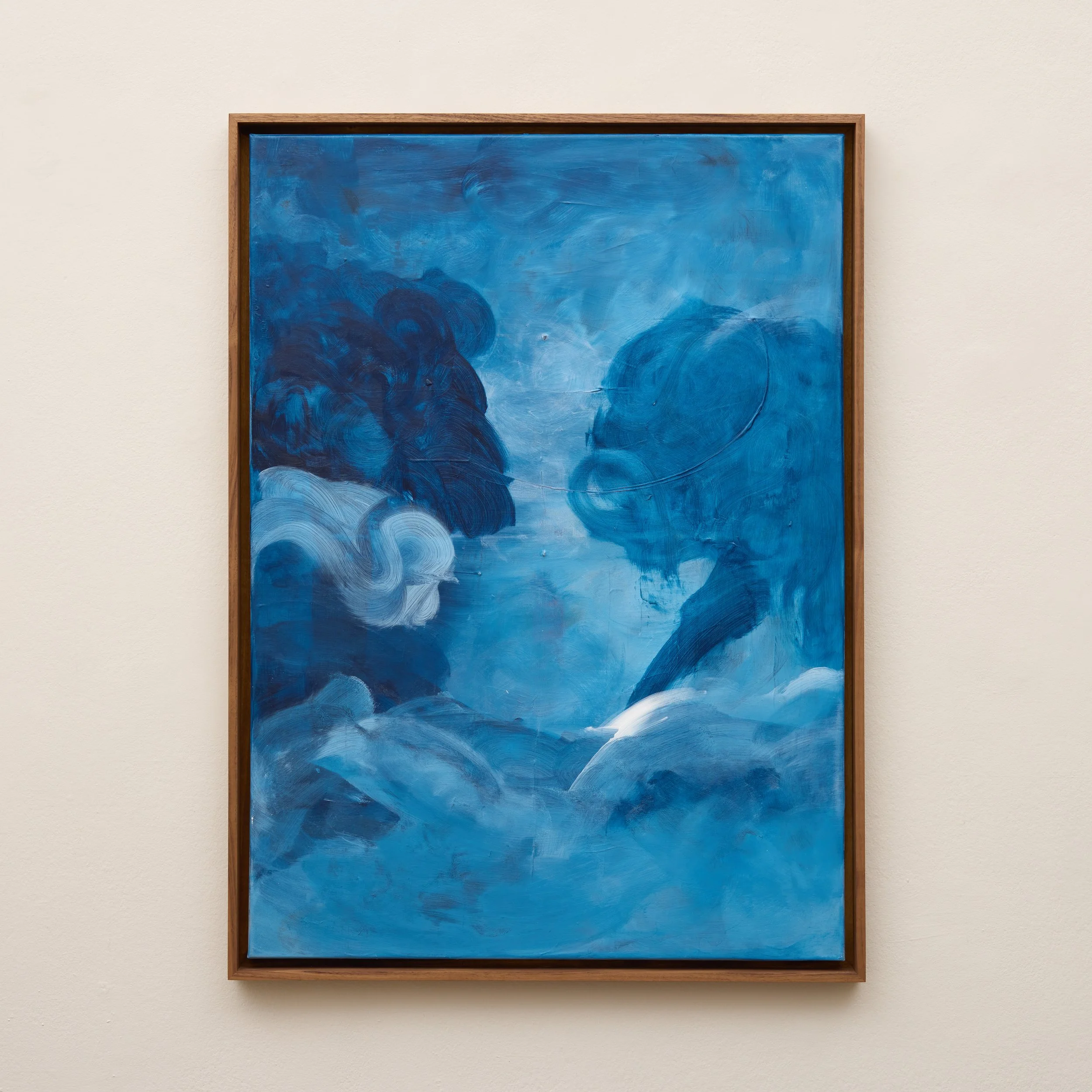 An abstract blue painting with circular and swirling patterns, framed in a light wood frame, hanging on a white wall.
