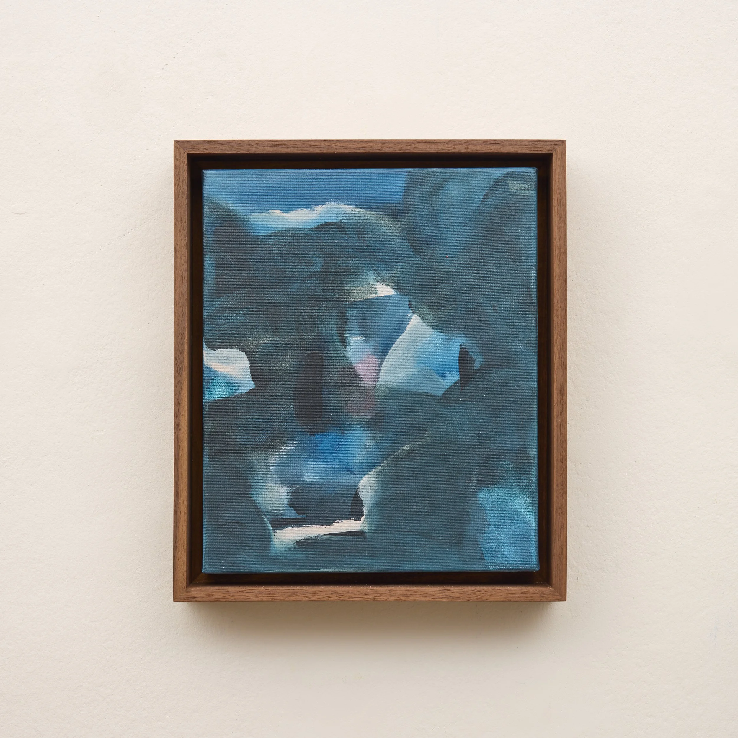 Close-up of a framed painting hanging on a plain wall, depicting a dark, cloudy sky with mountain tops.