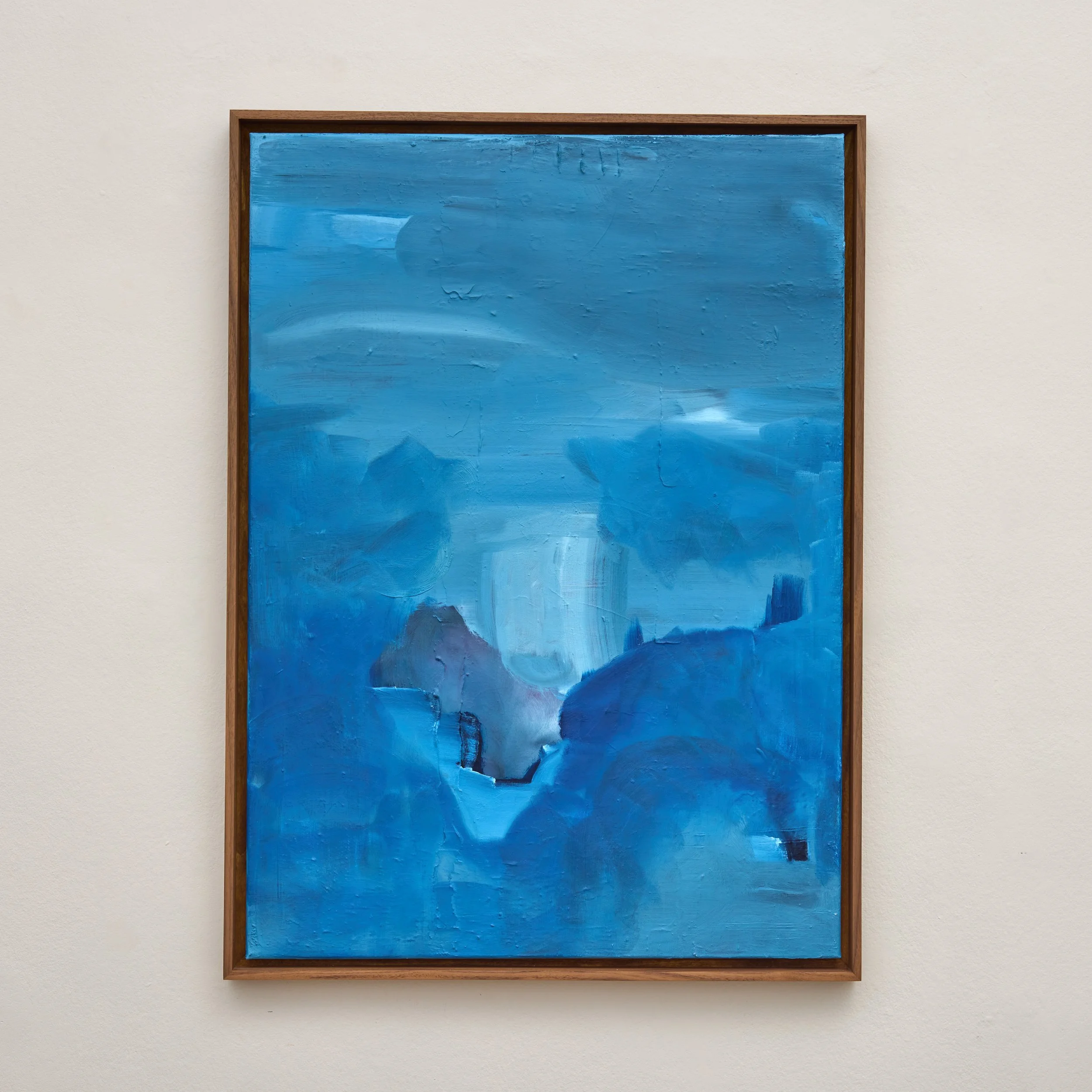 An abstract painting with a textured blue background, framed in wood, hanging on a white wall.