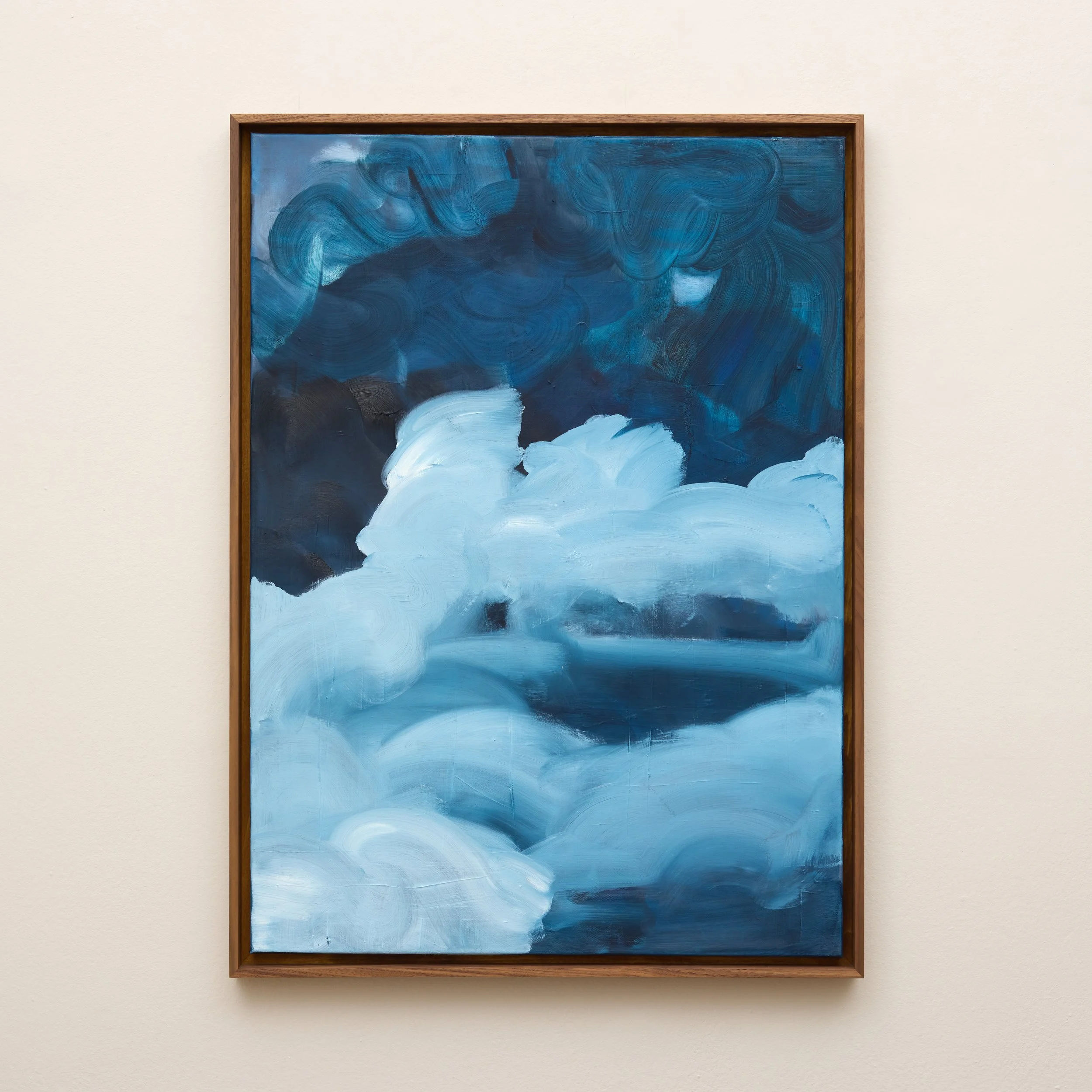 An abstract painting with blue, white, and dark gray swirling brushstrokes framed in wood, displayed on a cream wall.