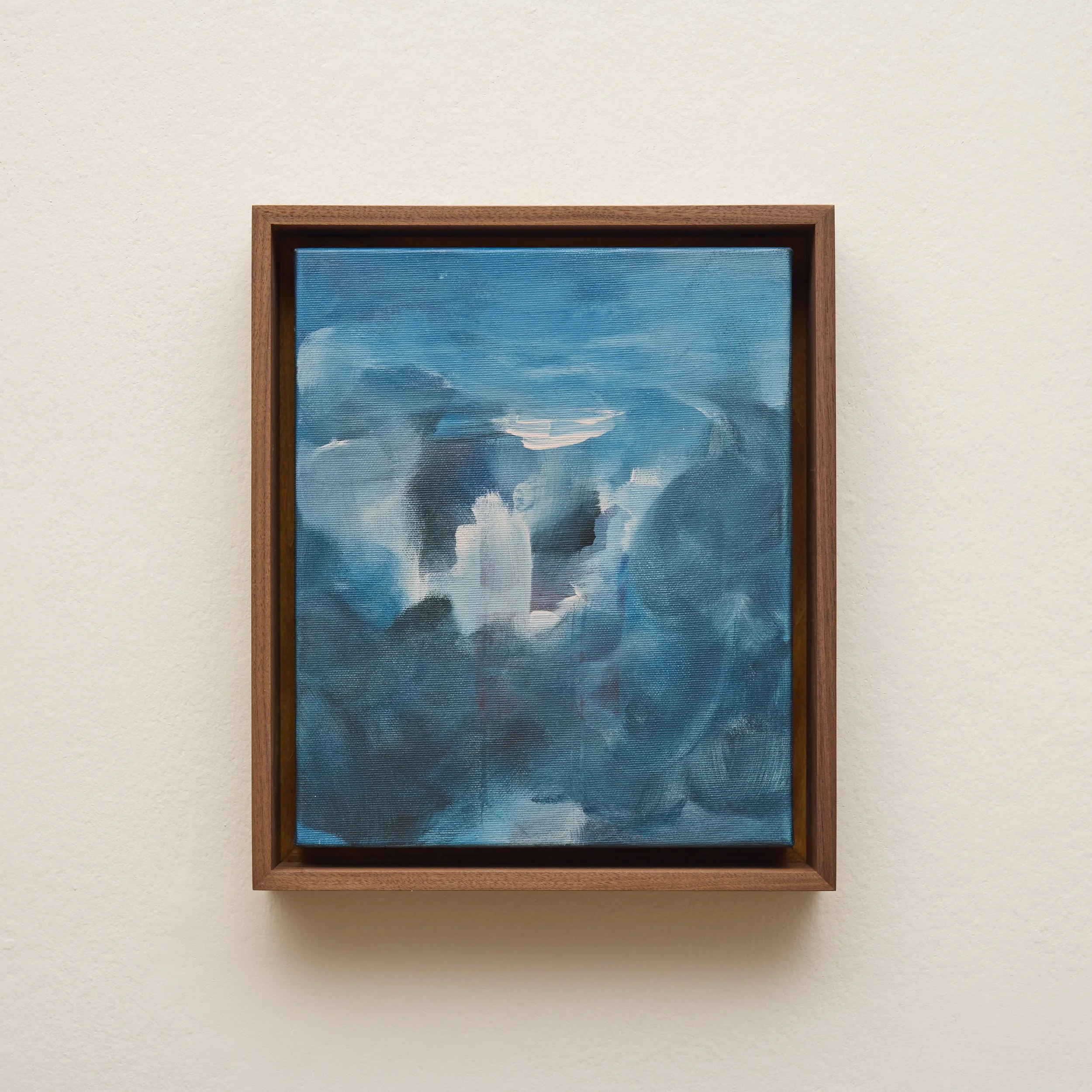 A framed painting of blue sky with white clouds hanging on a light-colored wall.