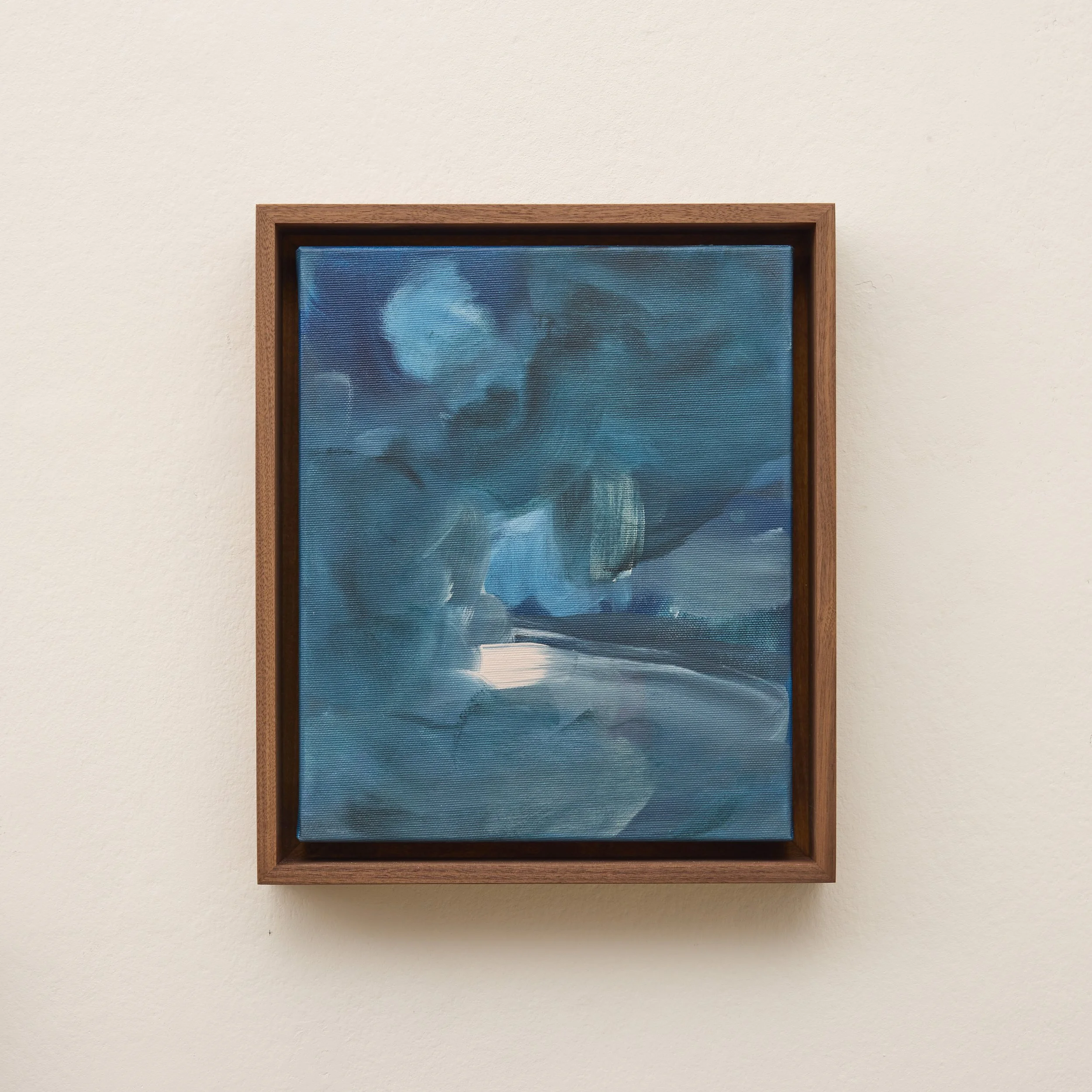 Framed abstract blue painting on a white wall.