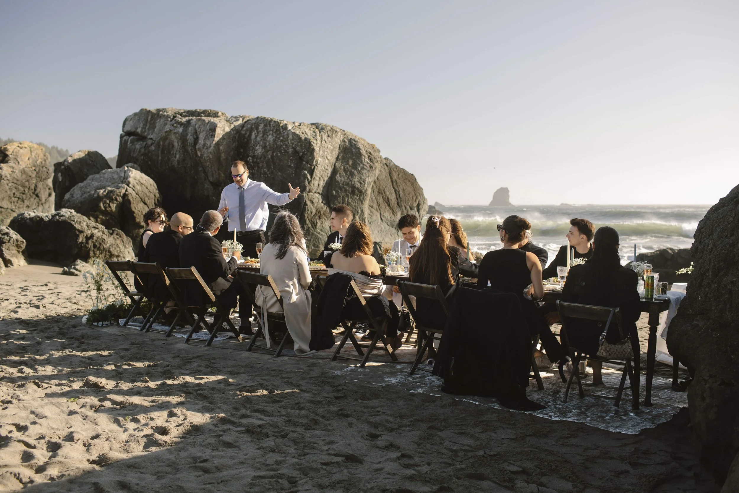 Micro wedding reception dinner on the Oregon Coast with long table set beside ocean cliffs.