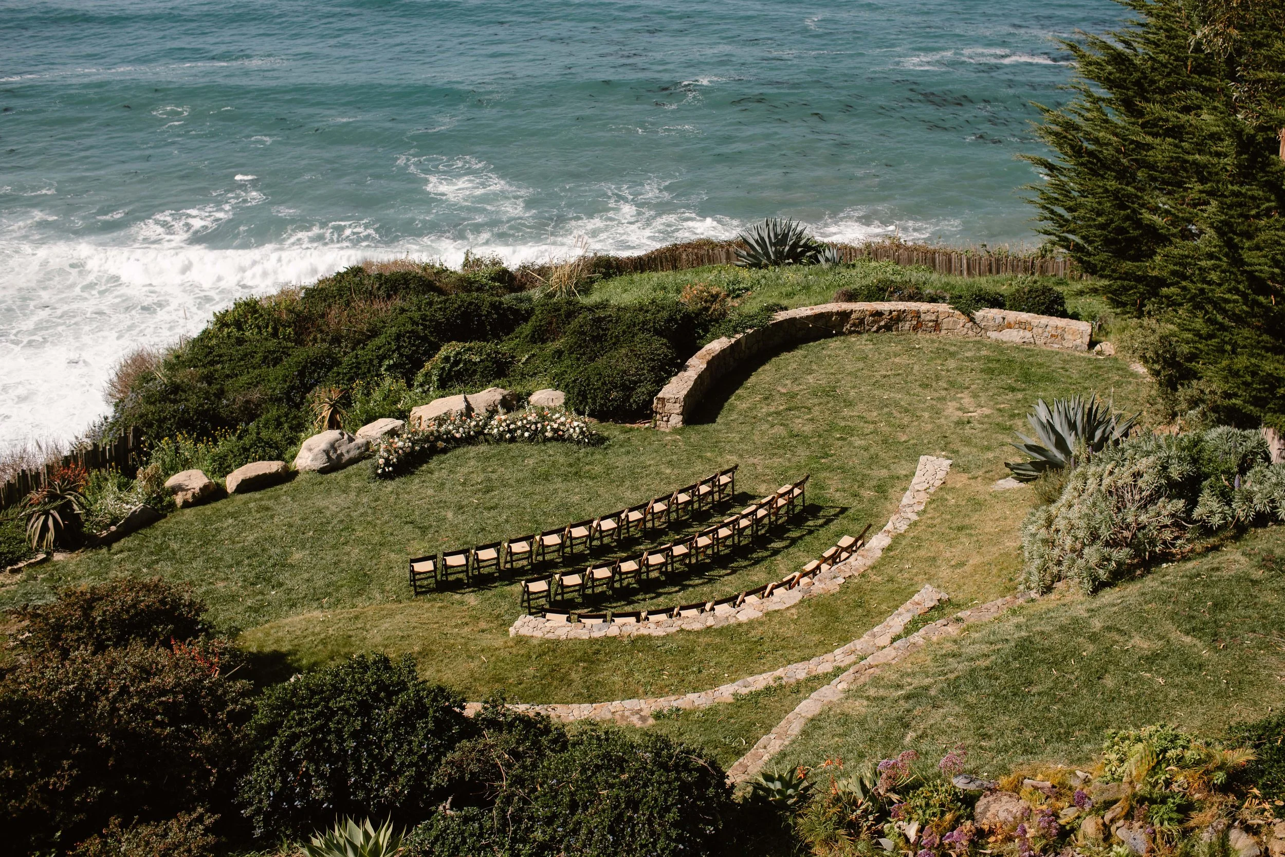 Airbnb wedding ceremony setup on a grassy cliff overlooking the ocean.