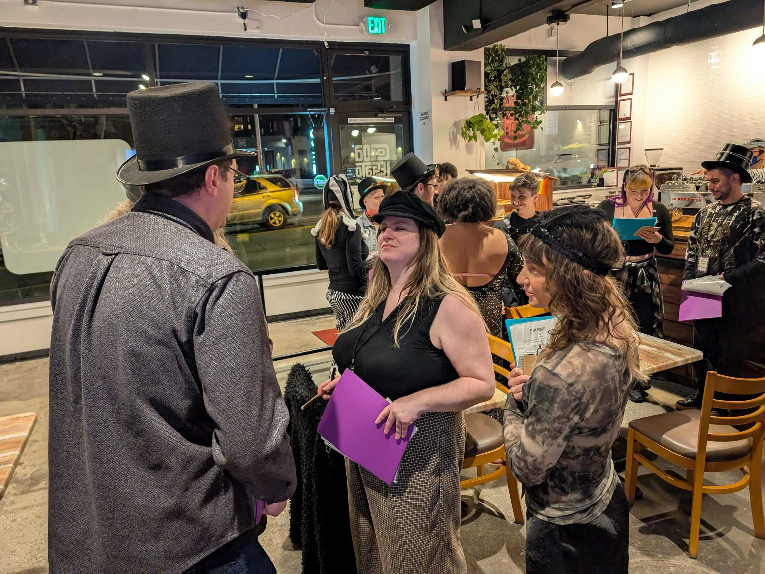 Four murder mystery players stand in a circle holding character packets and debating clues as part of the investigation.